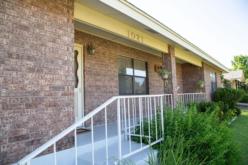 Brick exterior featuring a covered porch, white railing, and decorative house numbers