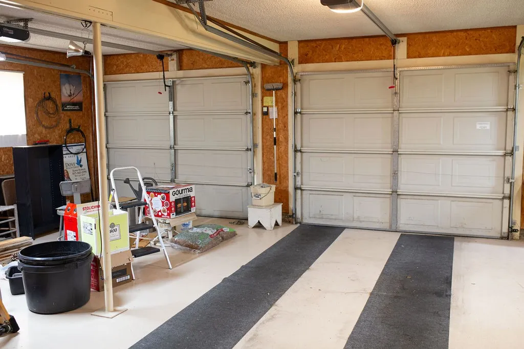 Two overhead garage doors, exposed wood-finish walls, and a painted concrete floor