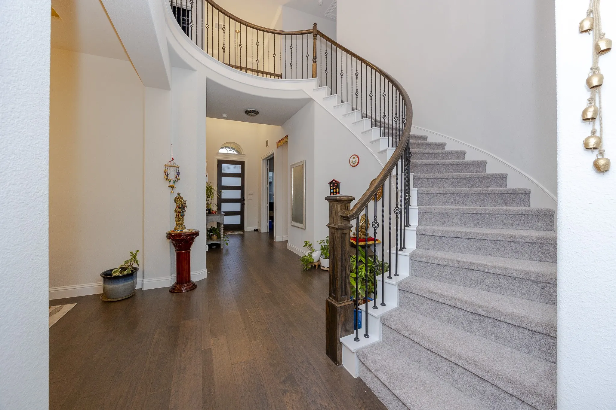 Grand entry with dark wood-finish flooring, a curved staircase with carpeted treads, and a wrought iron and wood banister