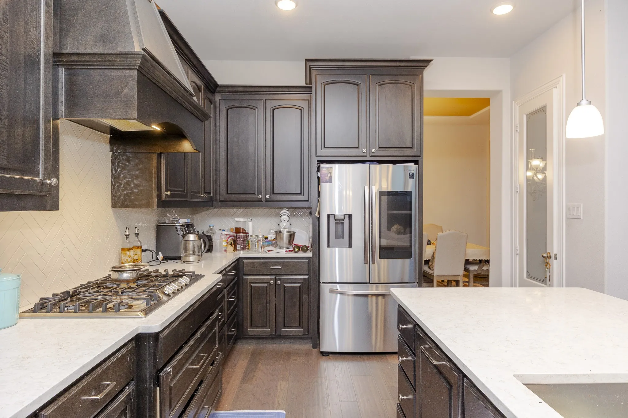 Kitchen featuring dark wood-finish cabinetry, light countertops, stainless steel appliances, and a gas range
