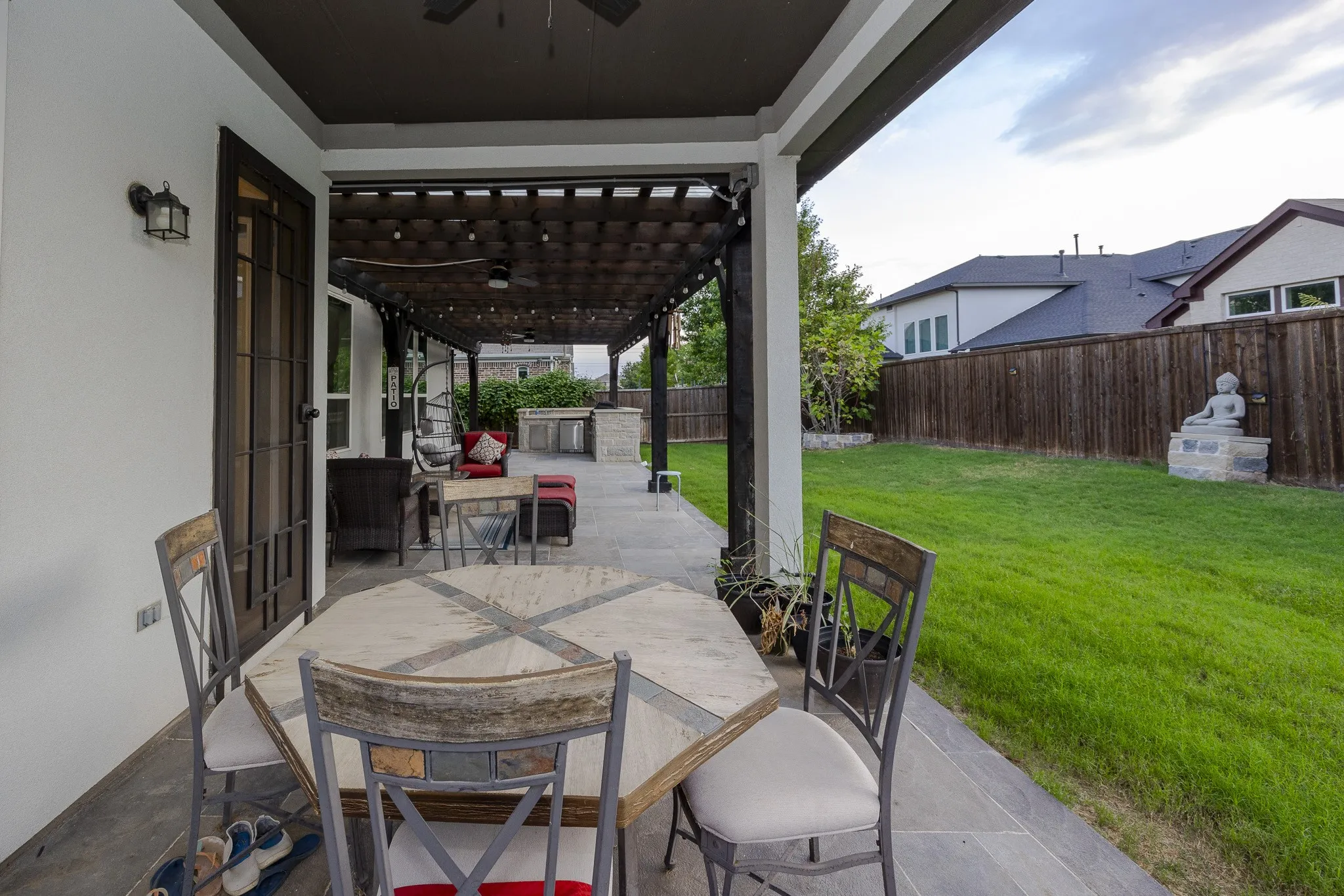 Expansive outdoor living area featuring a covered patio, a wooden pergola, and a manicured lawn