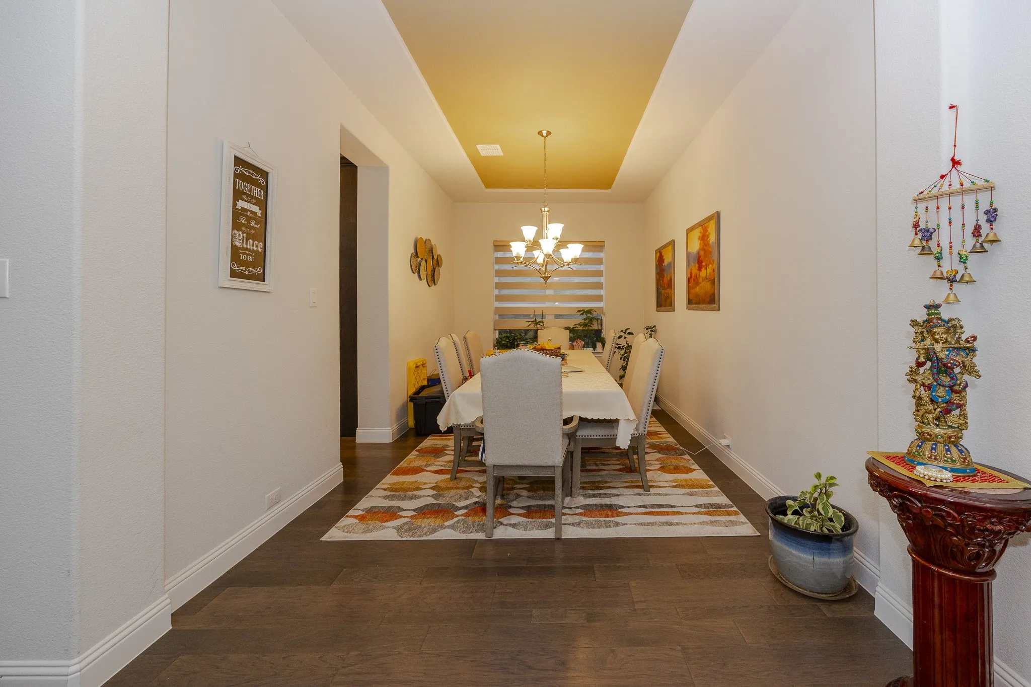 Recessed ceiling with an accent color, wood-finish flooring, and a multi-light chandelier
