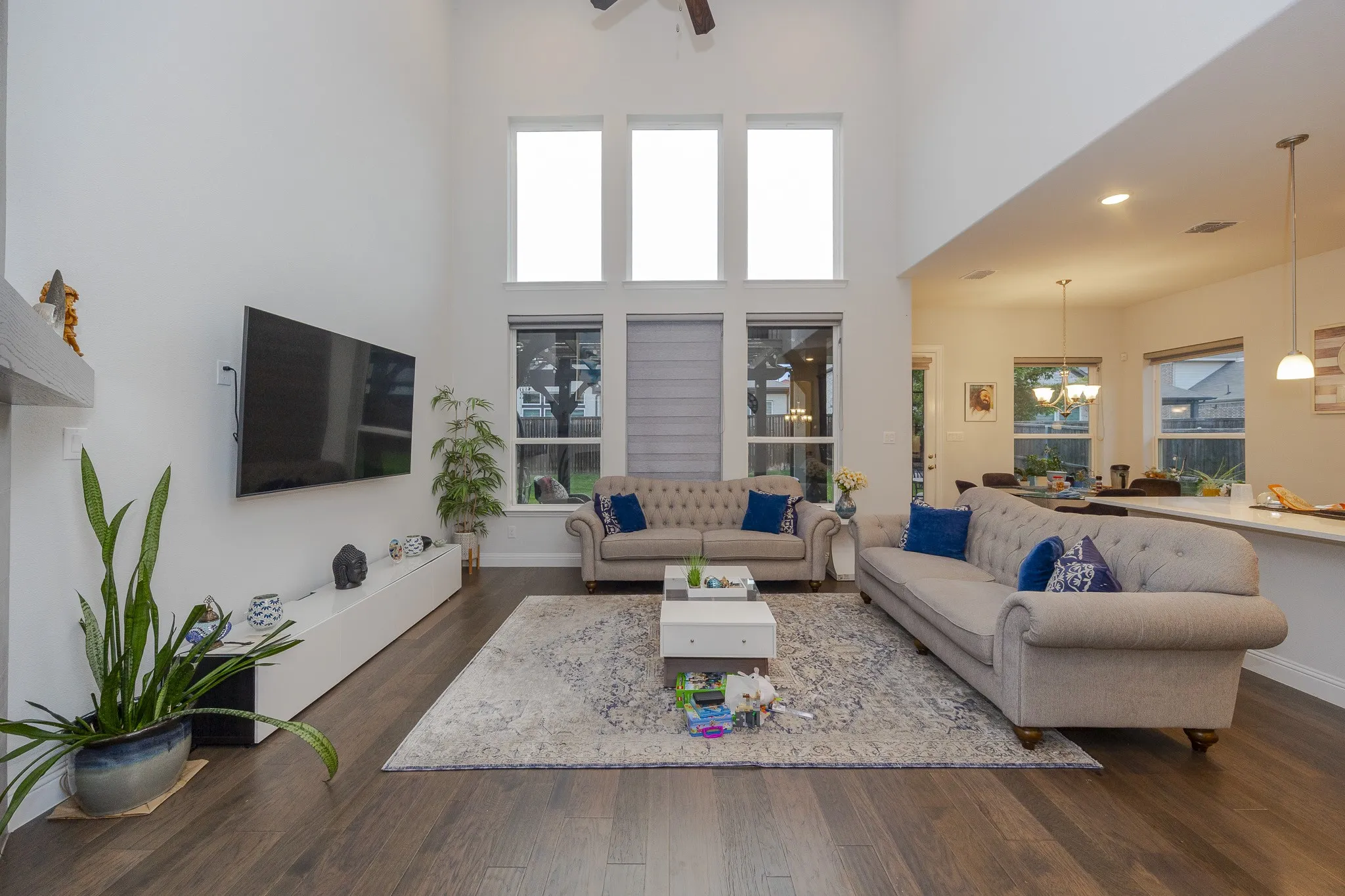 Soaring ceilings with transom windows, wood-finish flooring, recessed lighting, and a white floating media console