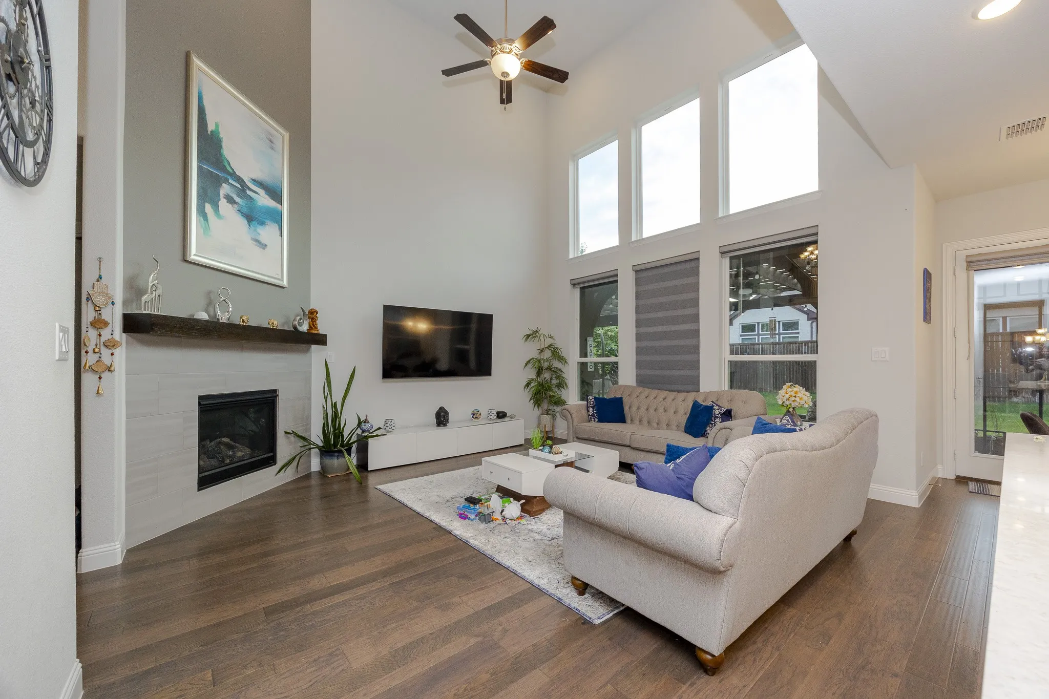 Vaulted ceiling with a ceiling fan, recessed lighting, wood-finish flooring, and a fireplace with a wood mantel