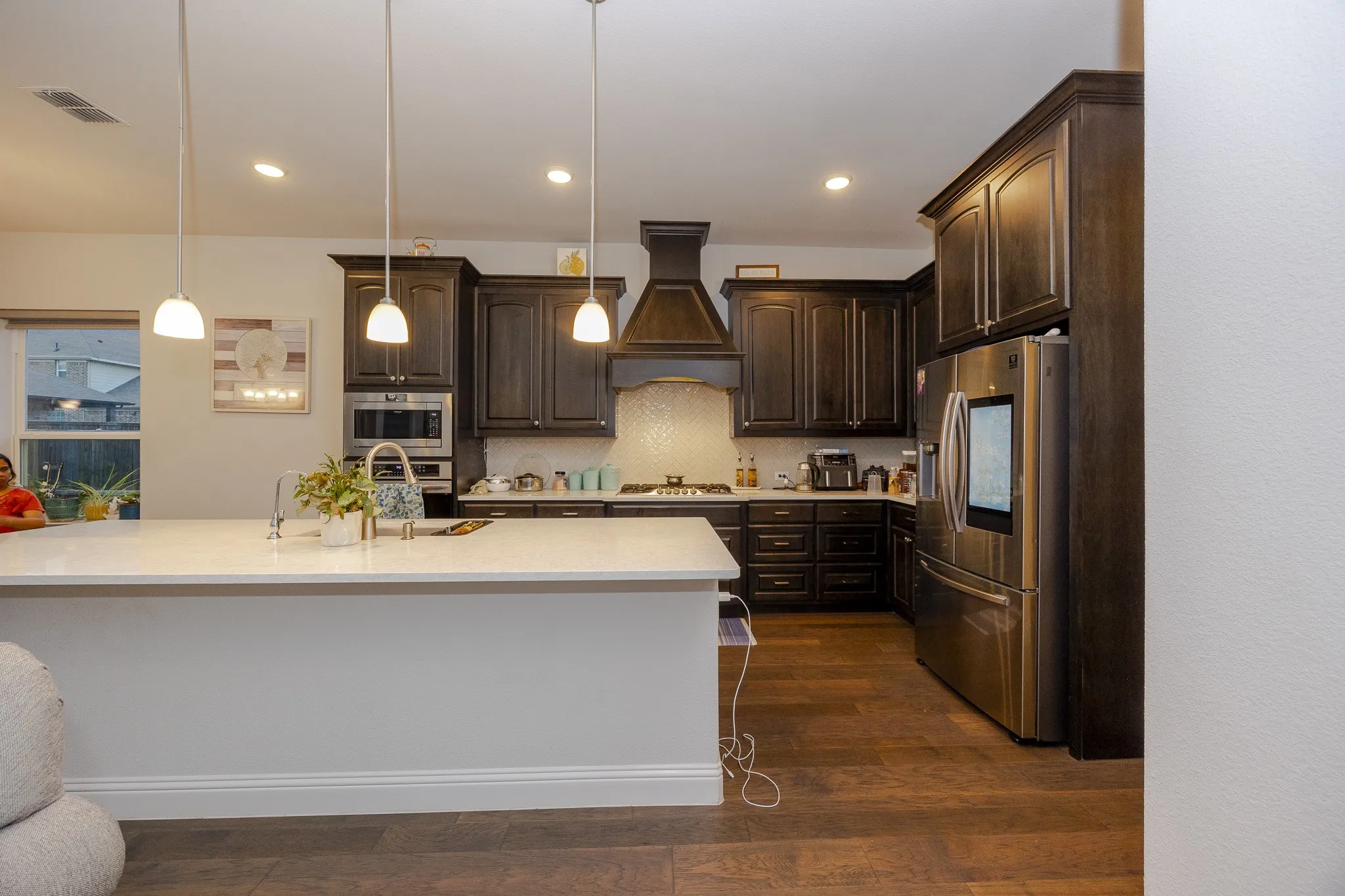 Kitchen featuring dark wood-finish cabinetry, stainless steel appliances, a center island with pendant lighting, and wood-finish flooring