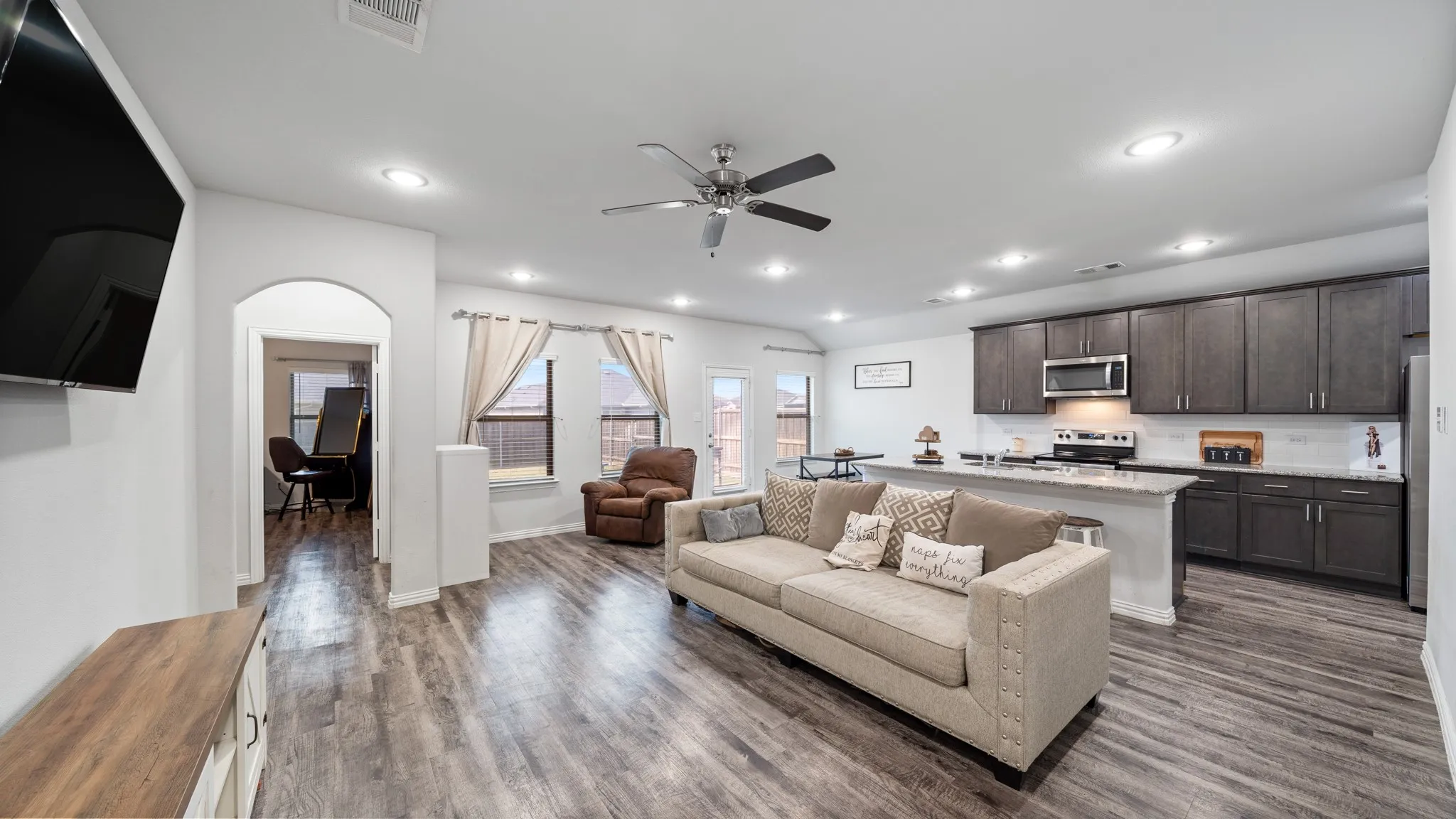 Open-concept living space with wood-finish flooring, recessed lighting, and a ceiling fan