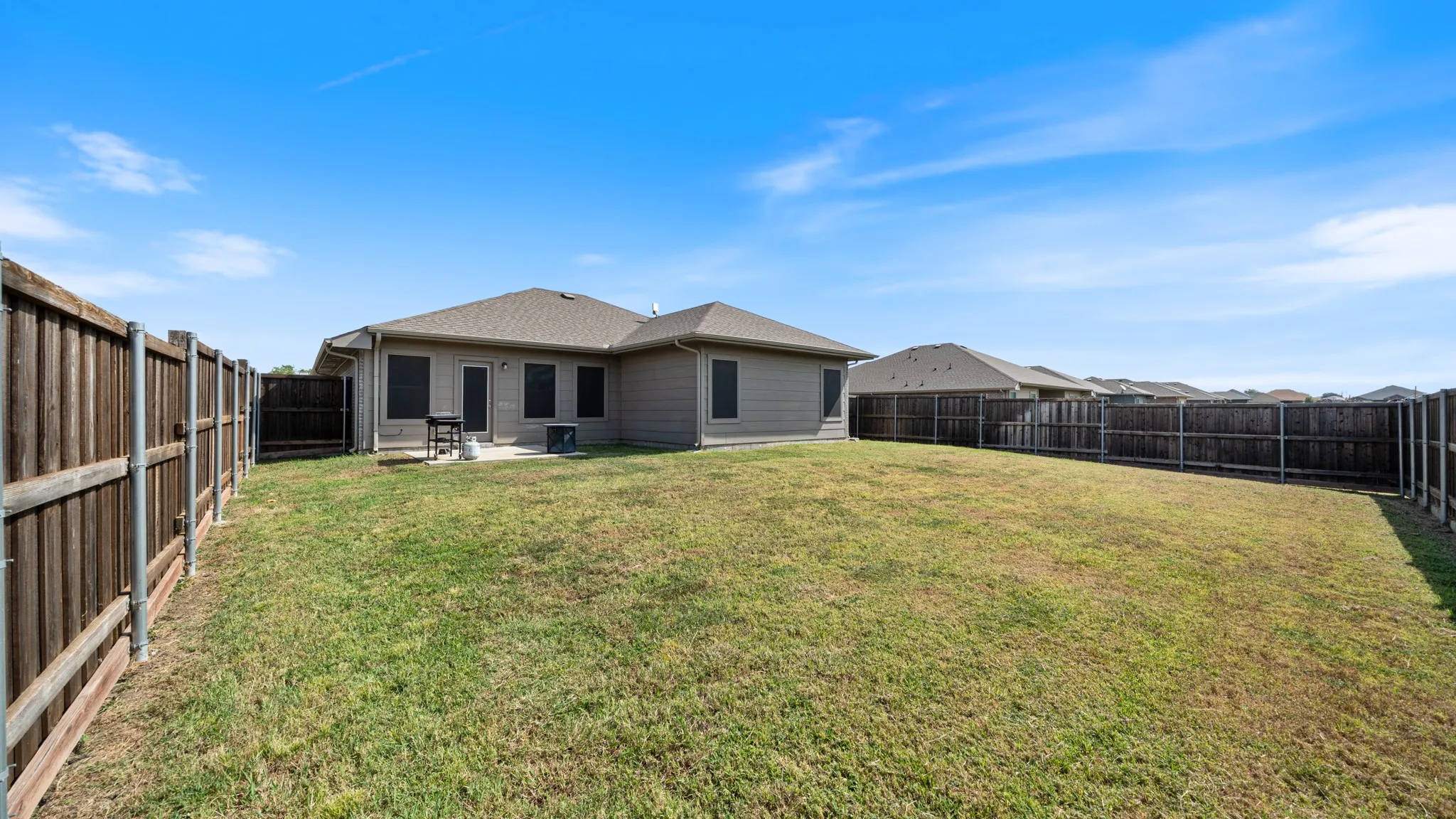 Expansive fenced backyard with a concrete patio