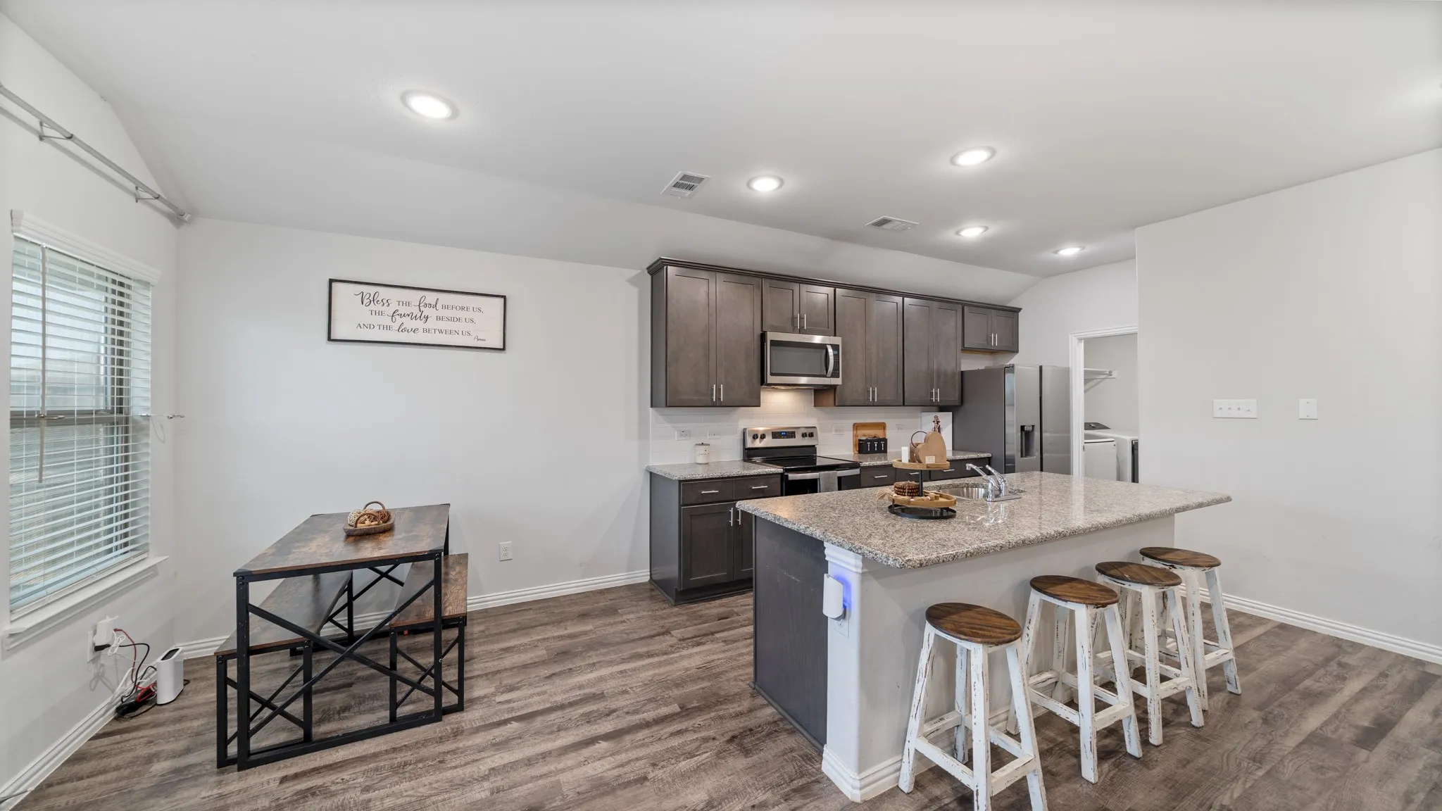 Kitchen featuring dark wood-finish cabinetry, stainless steel appliances, a large island with a stone countertop, and wood-finish flooring