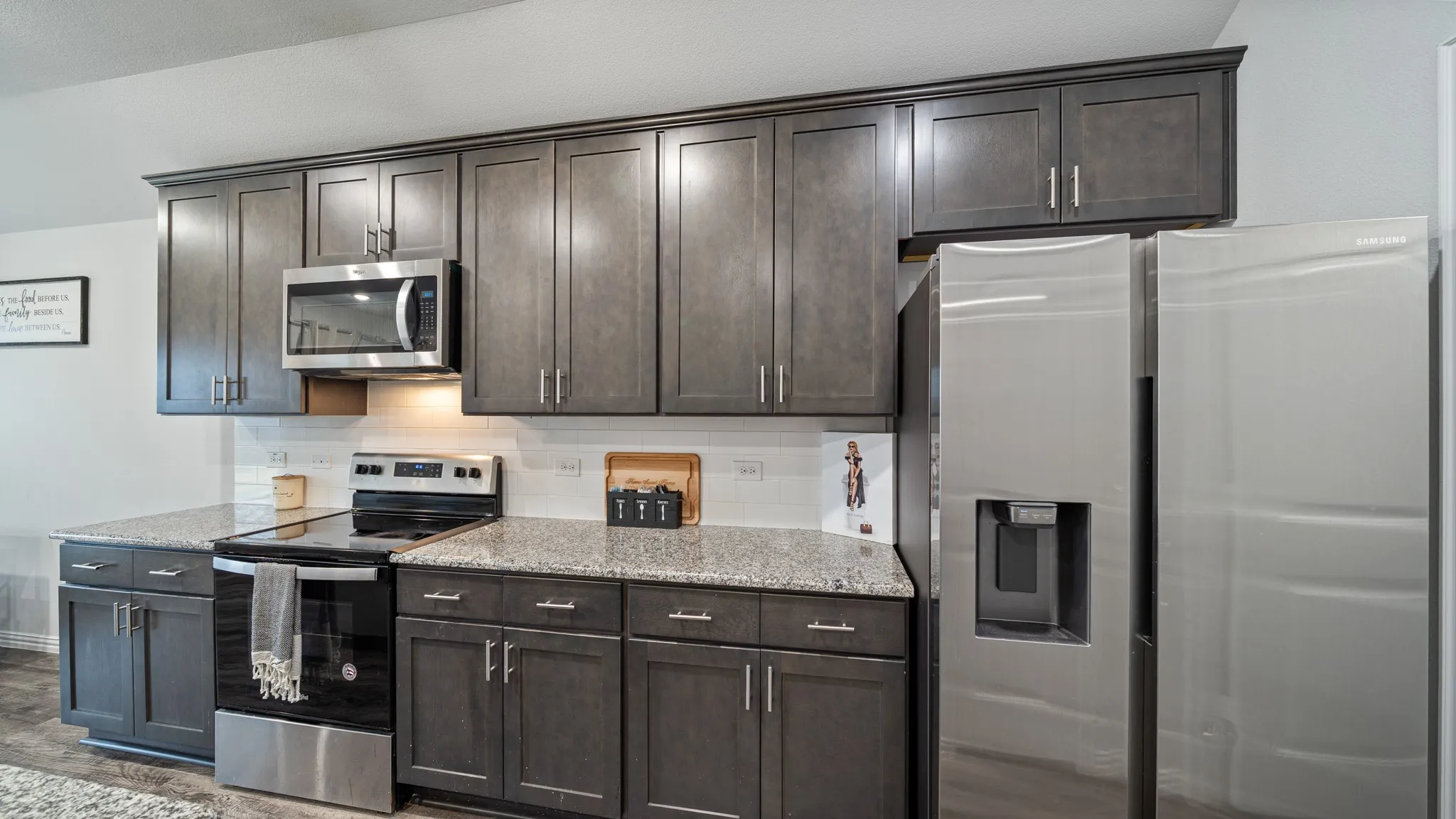 Kitchen featuring granite countertops, wood-finish cabinetry, stainless steel appliances, and a tiled backsplash