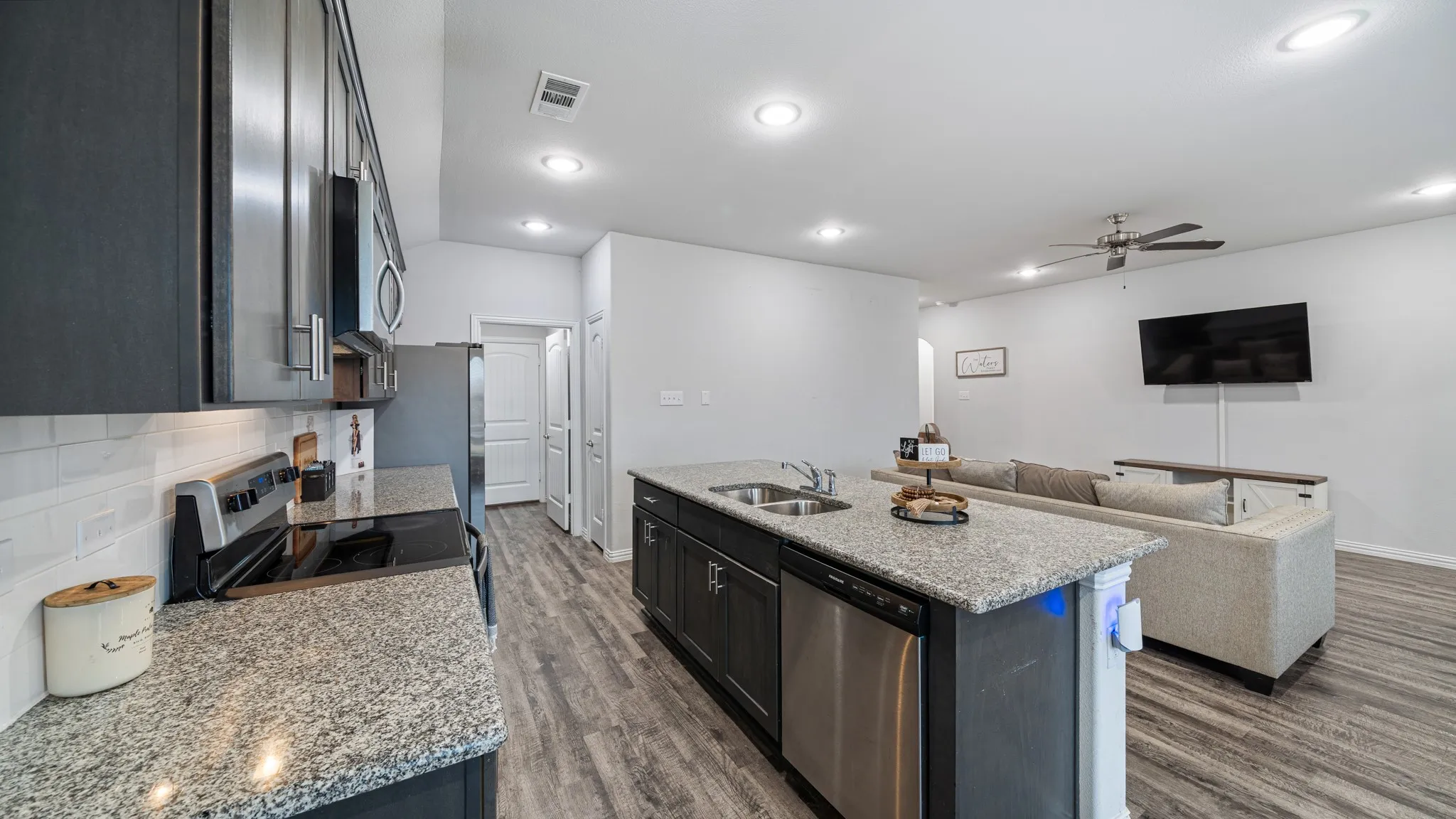 Kitchen island with an undermount double-basin sink, stainless steel dishwasher, and stone countertops