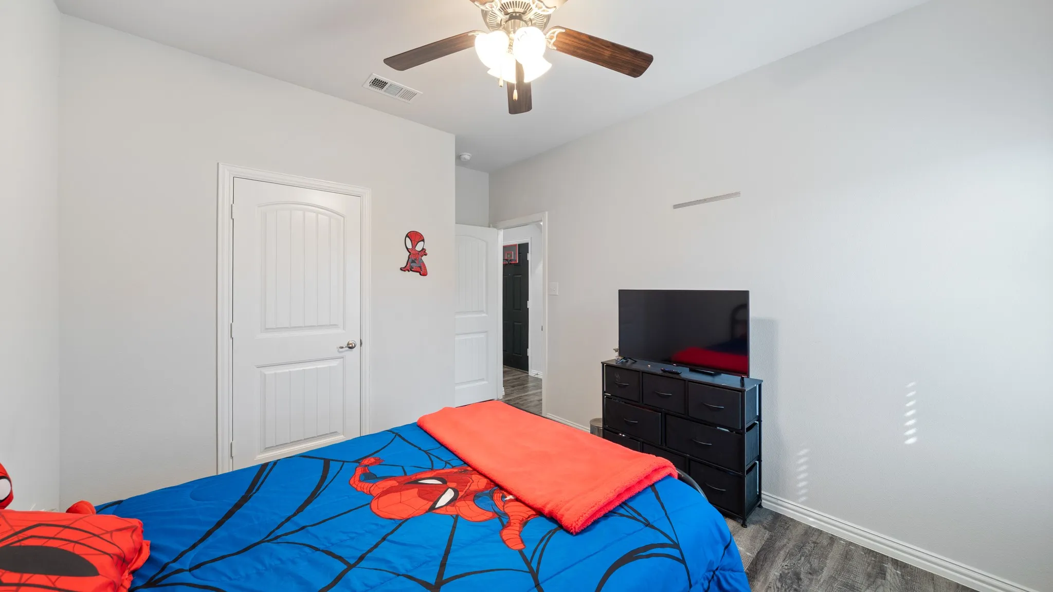 Wood-finish flooring, white paneled door, and a ceiling fan with integrated lighting
