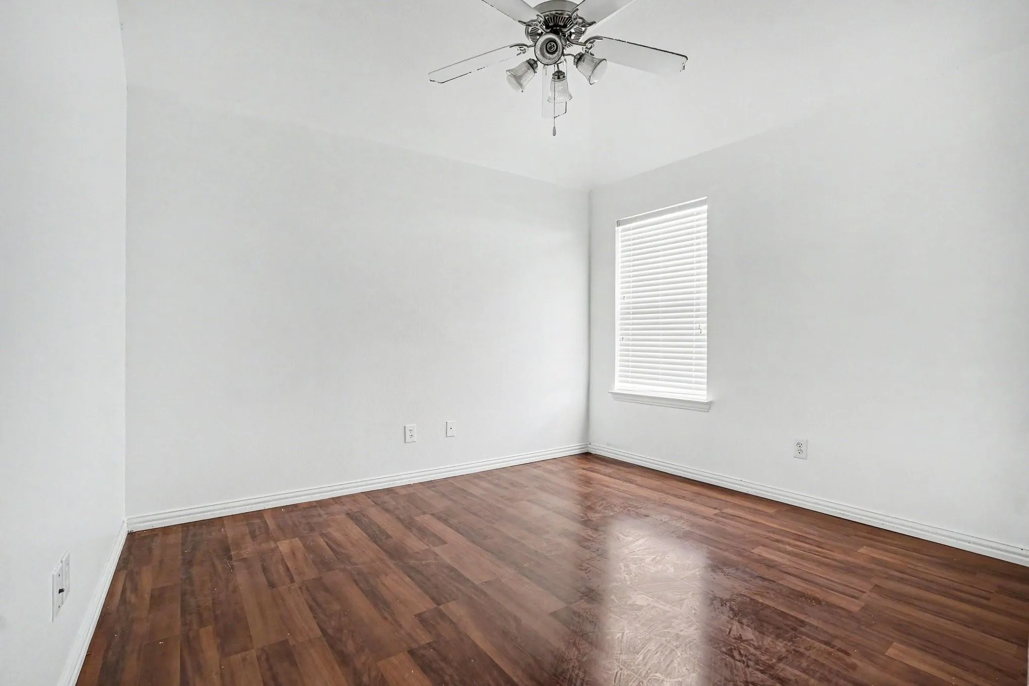 Wood-finish flooring, white walls, single window with blinds, and ceiling fan with integrated lighting