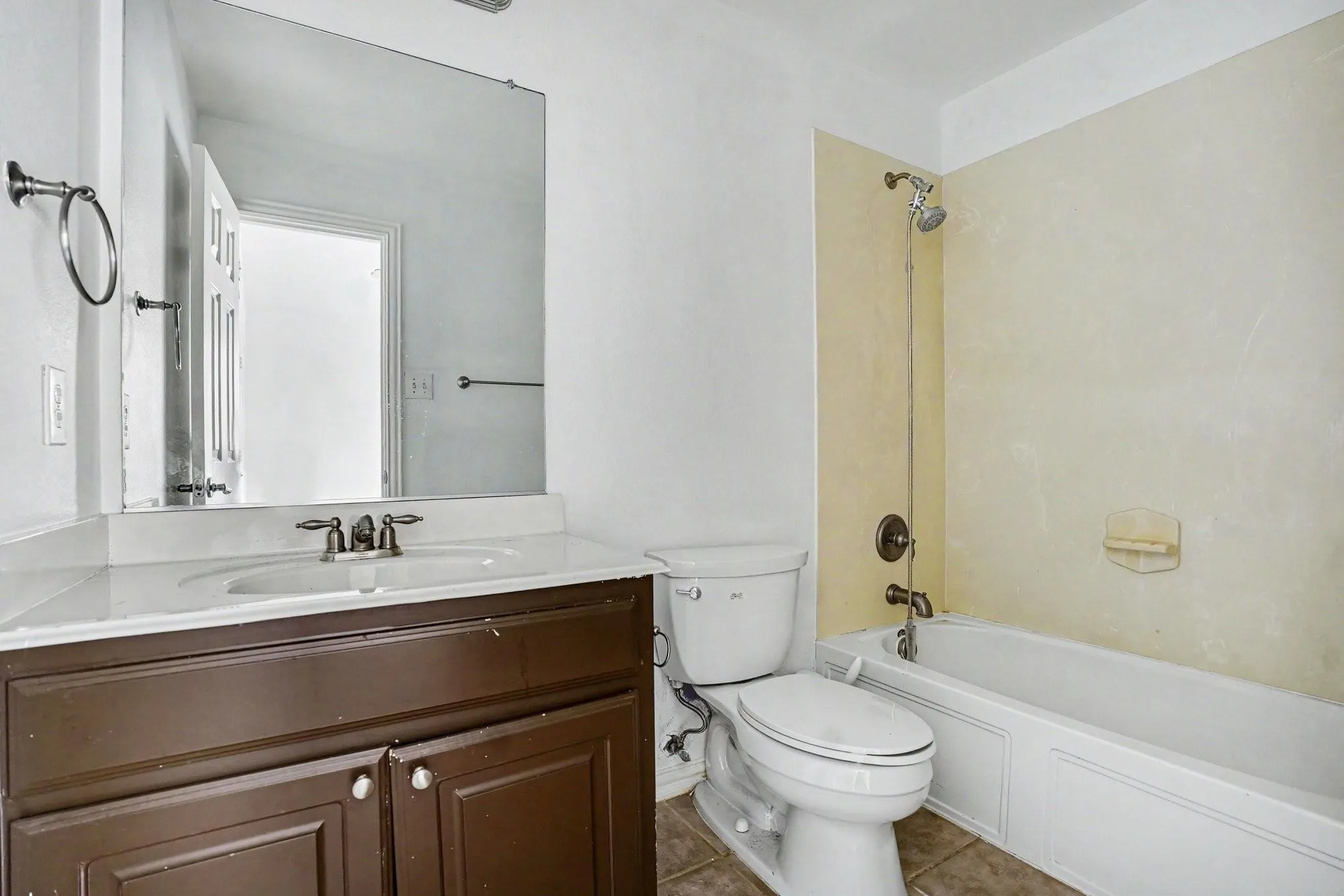 Vanity with a white countertop and integrated sink, bronze-finish faucet, and coordinating towel ring