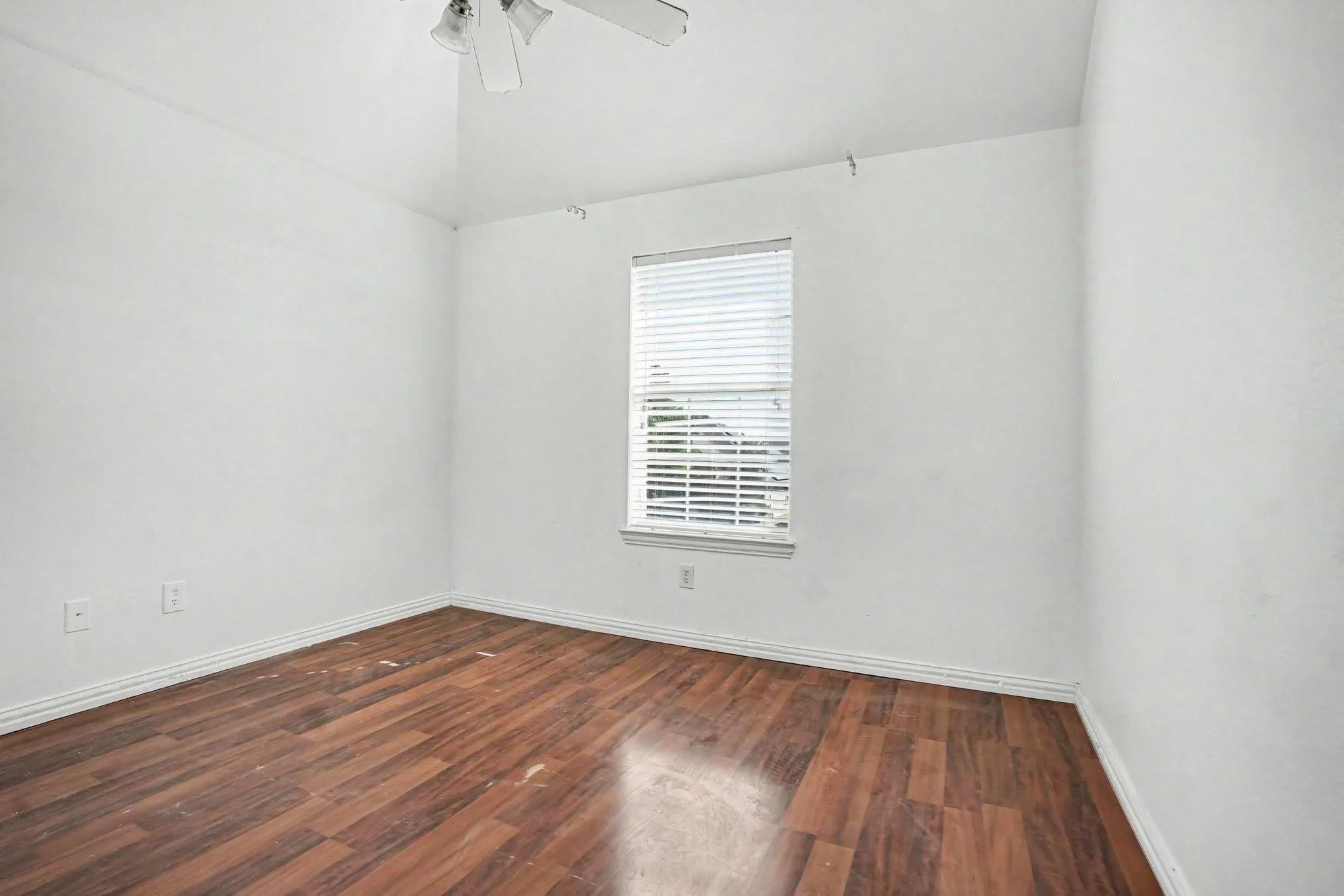 Vaulted ceiling with a ceiling fan, white window blinds, and wood-finish flooring