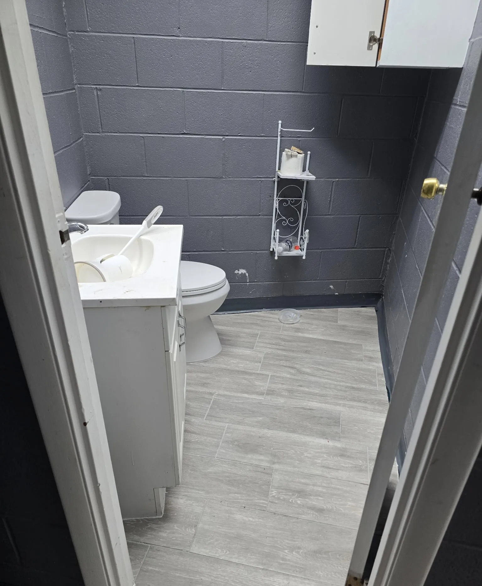 White vanity with integrated sink, modern toilet, and light-toned tile flooring