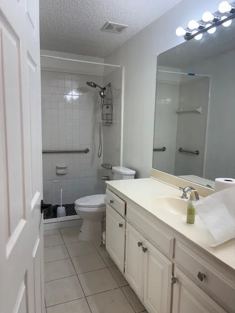 Bathroom featuring a vanity with integrated sink, a built-in mirror, overhead lighting, and tiled flooring
