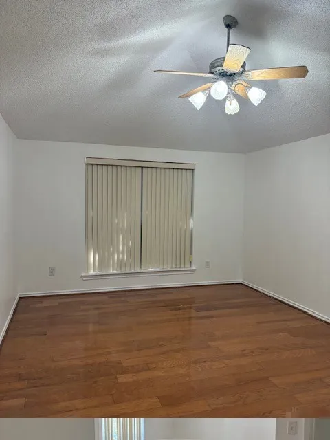 Wood-finish flooring, a window with vertical blinds, and a ceiling fan with integrated lighting