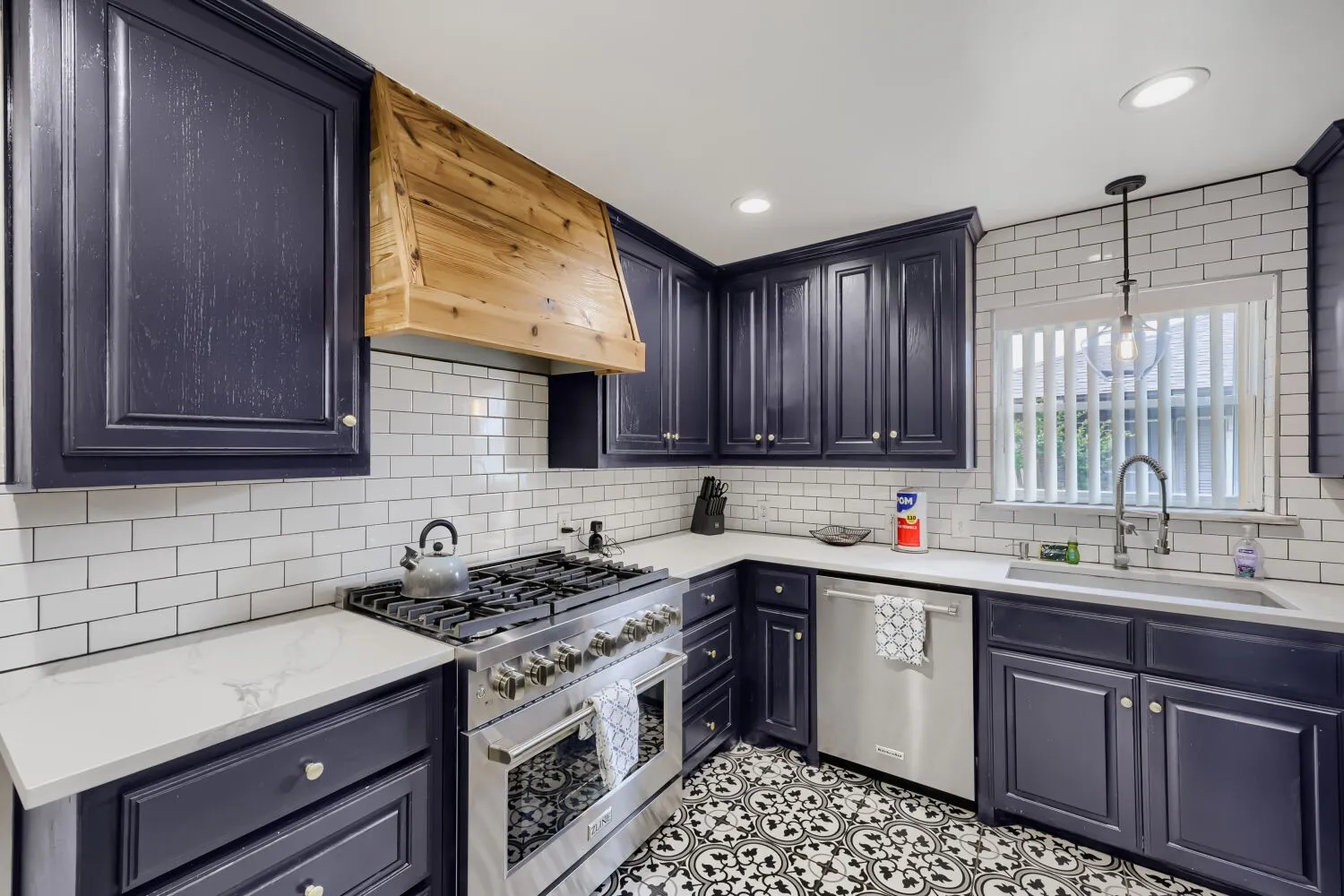 Kitchen featuring dark cabinetry, white subway tile backsplash, light-toned countertops, stainless steel appliances, and patterned floor​​‌​​​​‌​​‌‌​‌‌​​​‌‌​‌​‌​‌​​​‌​​ tile
