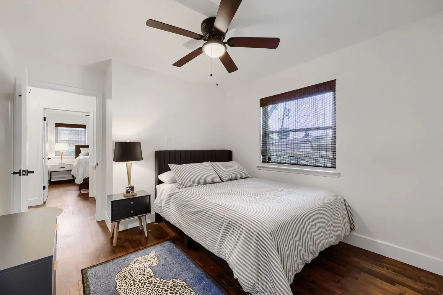 Hardwood-finish flooring, white walls, ceiling fan, window with blinds, and white trim
