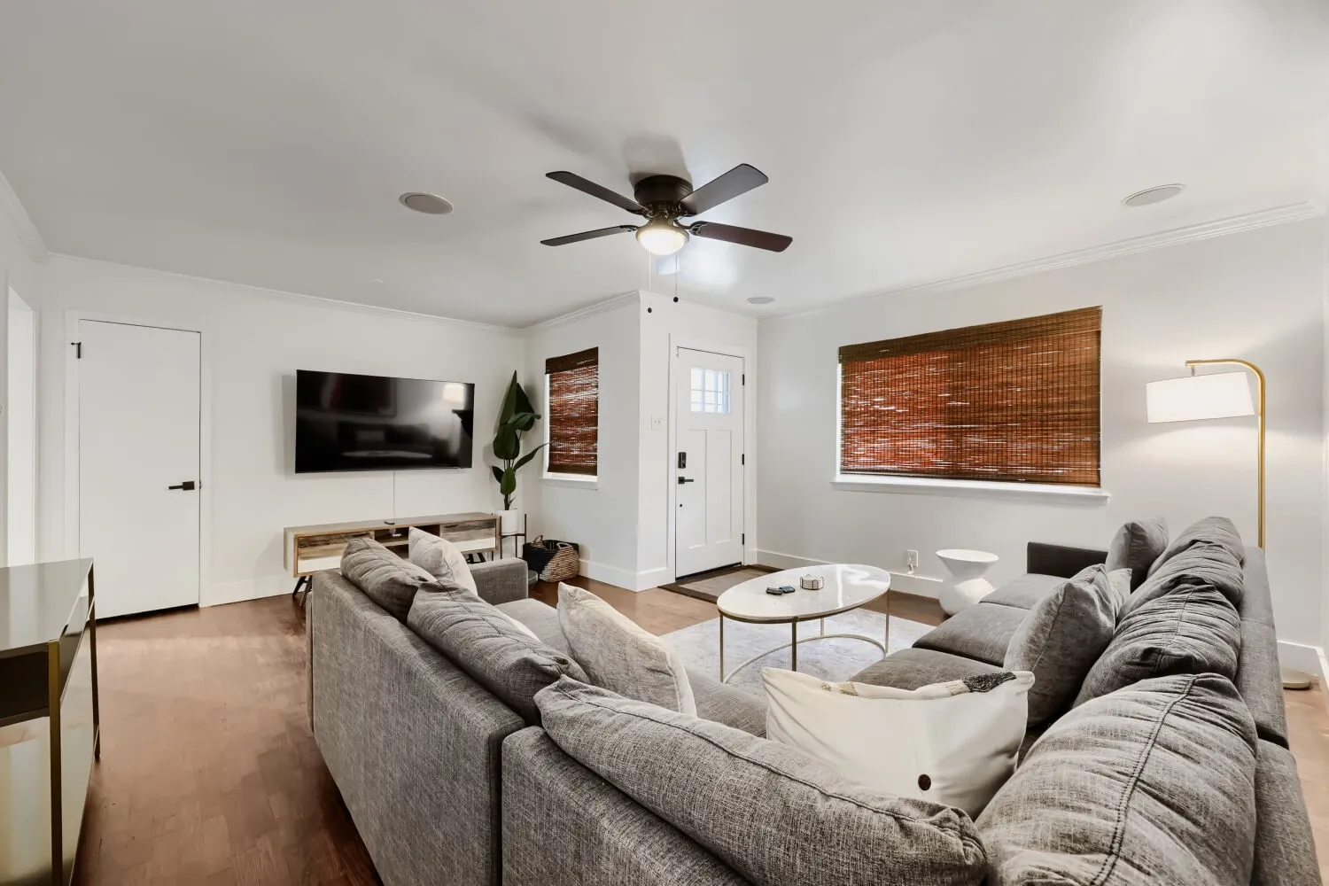 Hardwood-finish flooring, recessed ceiling lighting, ceiling fan, white paneled door with matte black hardware, and crown molding