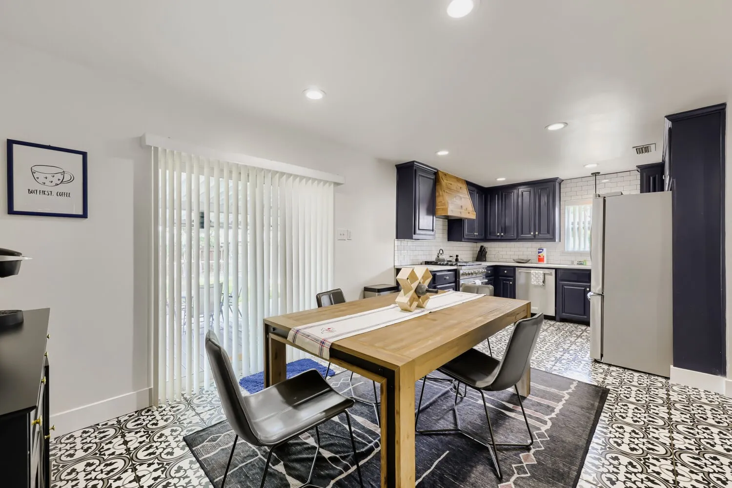 Stainless steel range, wood-finish range hood, white subway tile backsplash, dark-finish cabinetry, and light-finish countertops