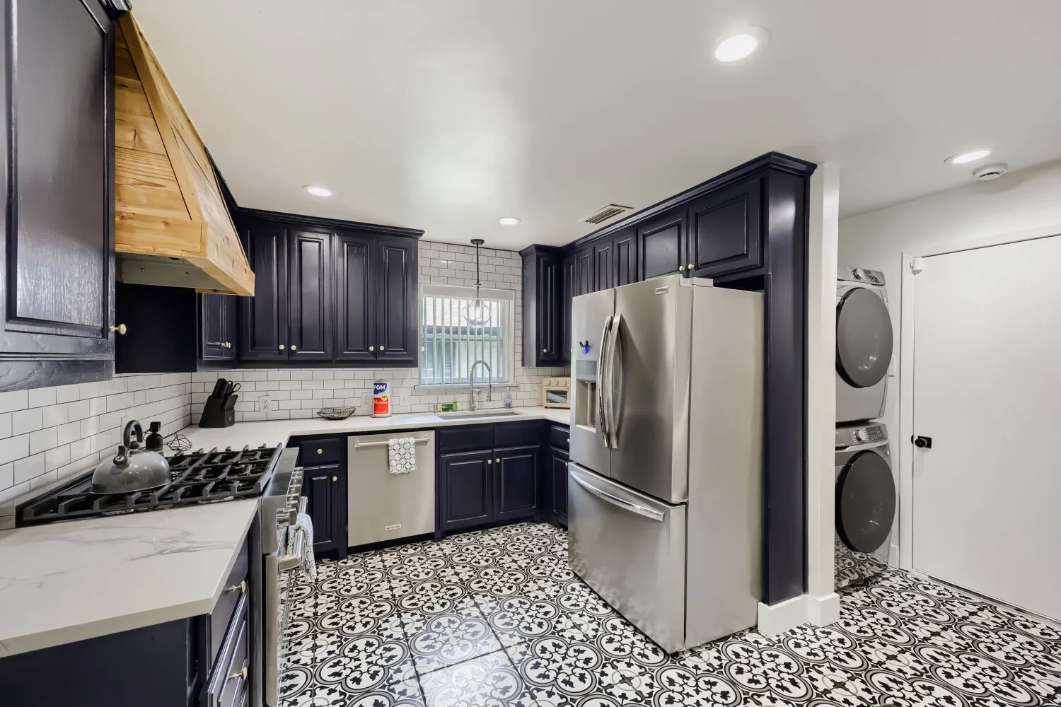 Kitchen featuring dark cabinetry, white subway tile backsplash, light-toned countertops, and patterned floor tile