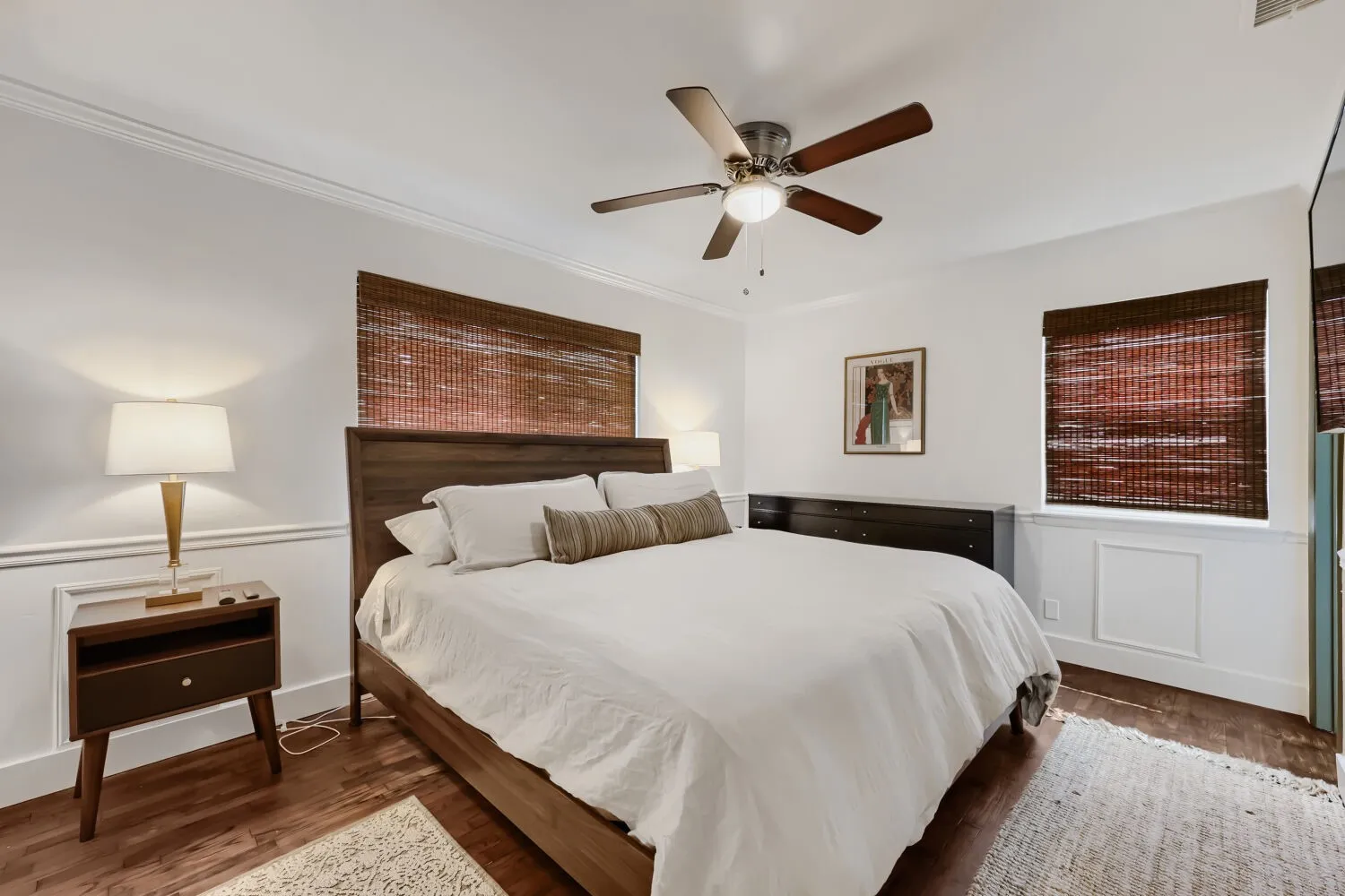 Hardwood flooring, crown molding, chair rail molding, ceiling fan with light fixture, and wood-finish window treatments
