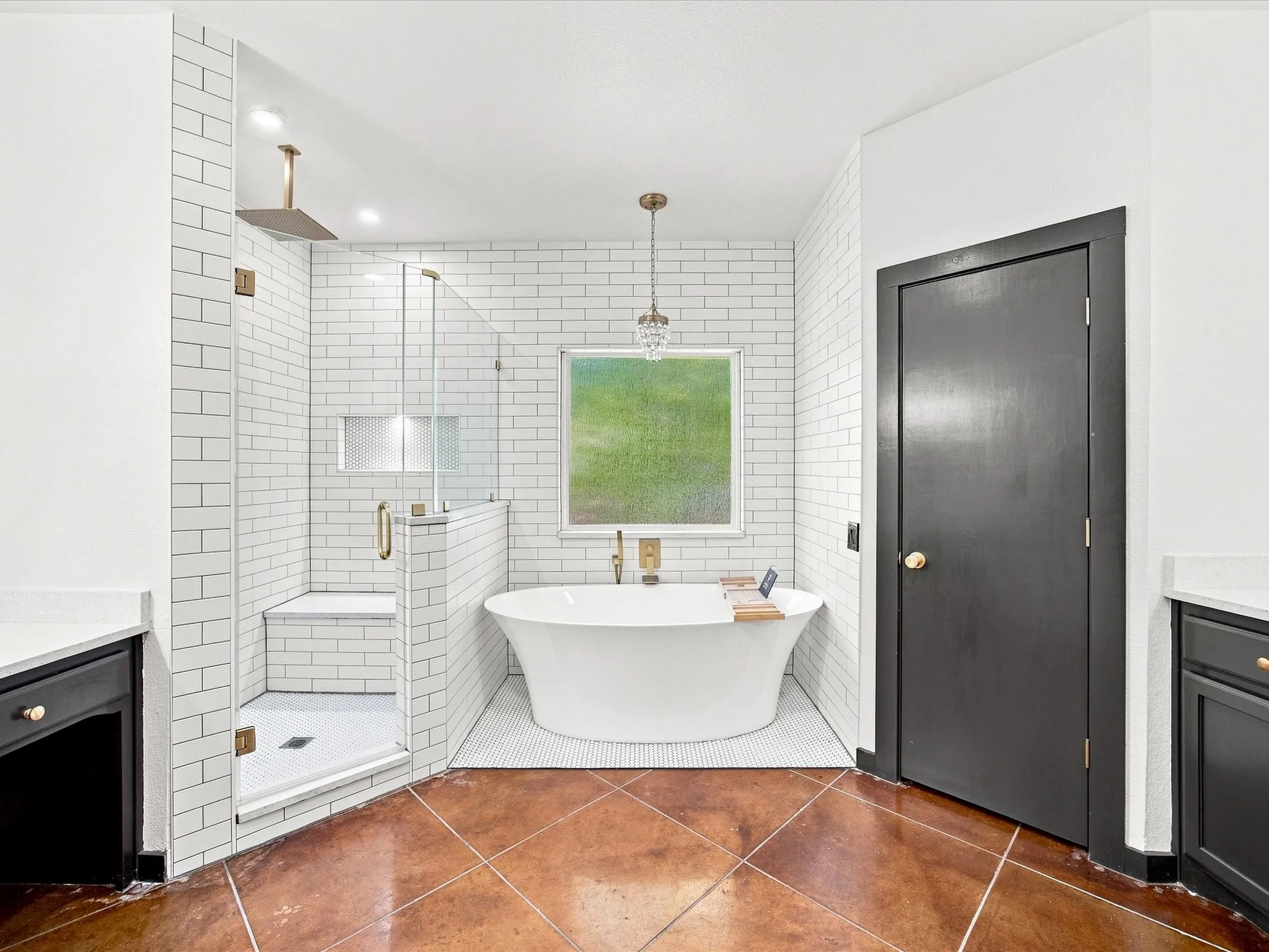 Freestanding soaking tub, glass-enclosed shower with subway tile surround, dual vanity with stone countertops, and warm-toned flooring