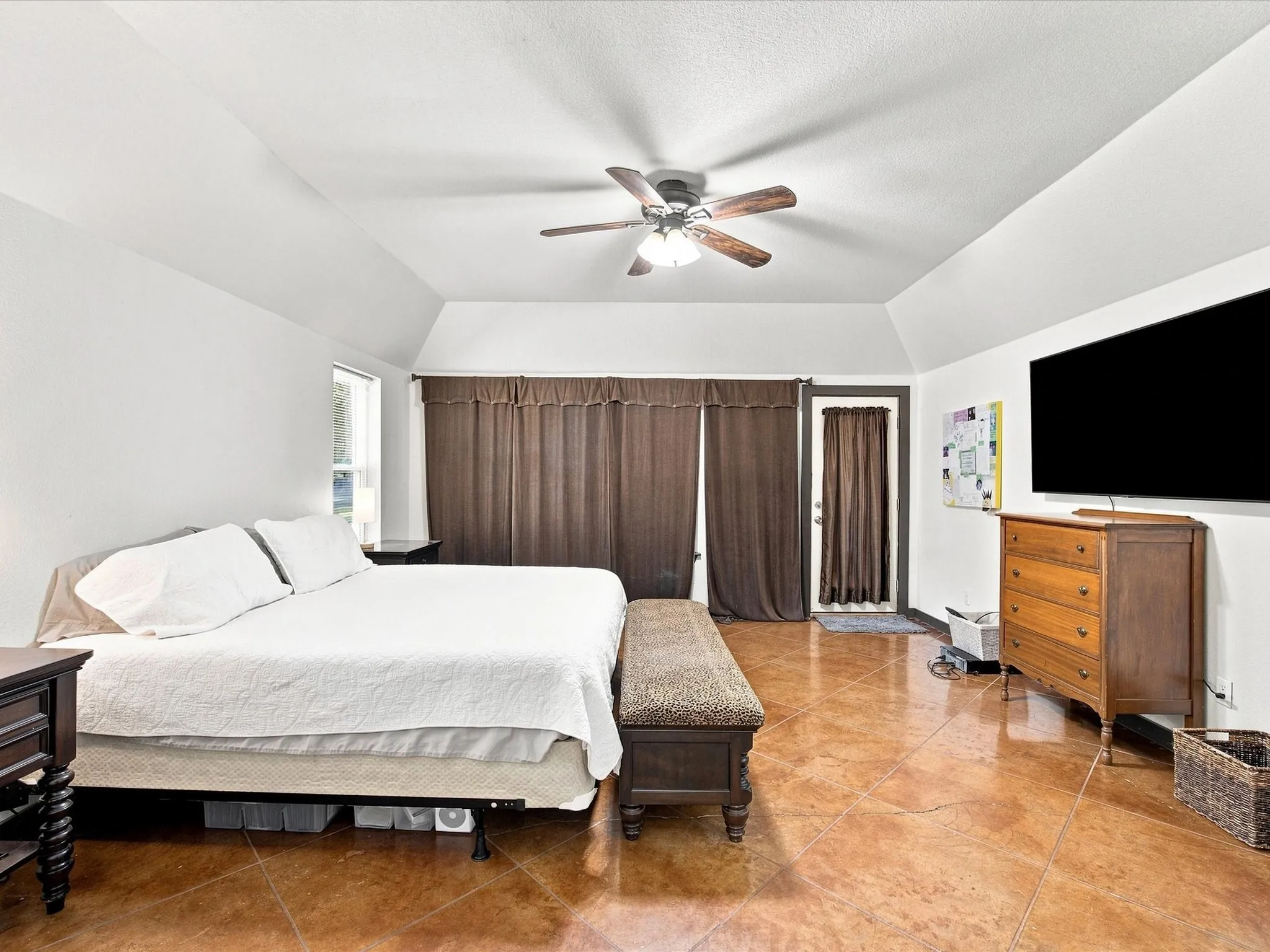 Vaulted ceilings with a ceiling fan, stained concrete flooring, and a glass-paneled exterior door