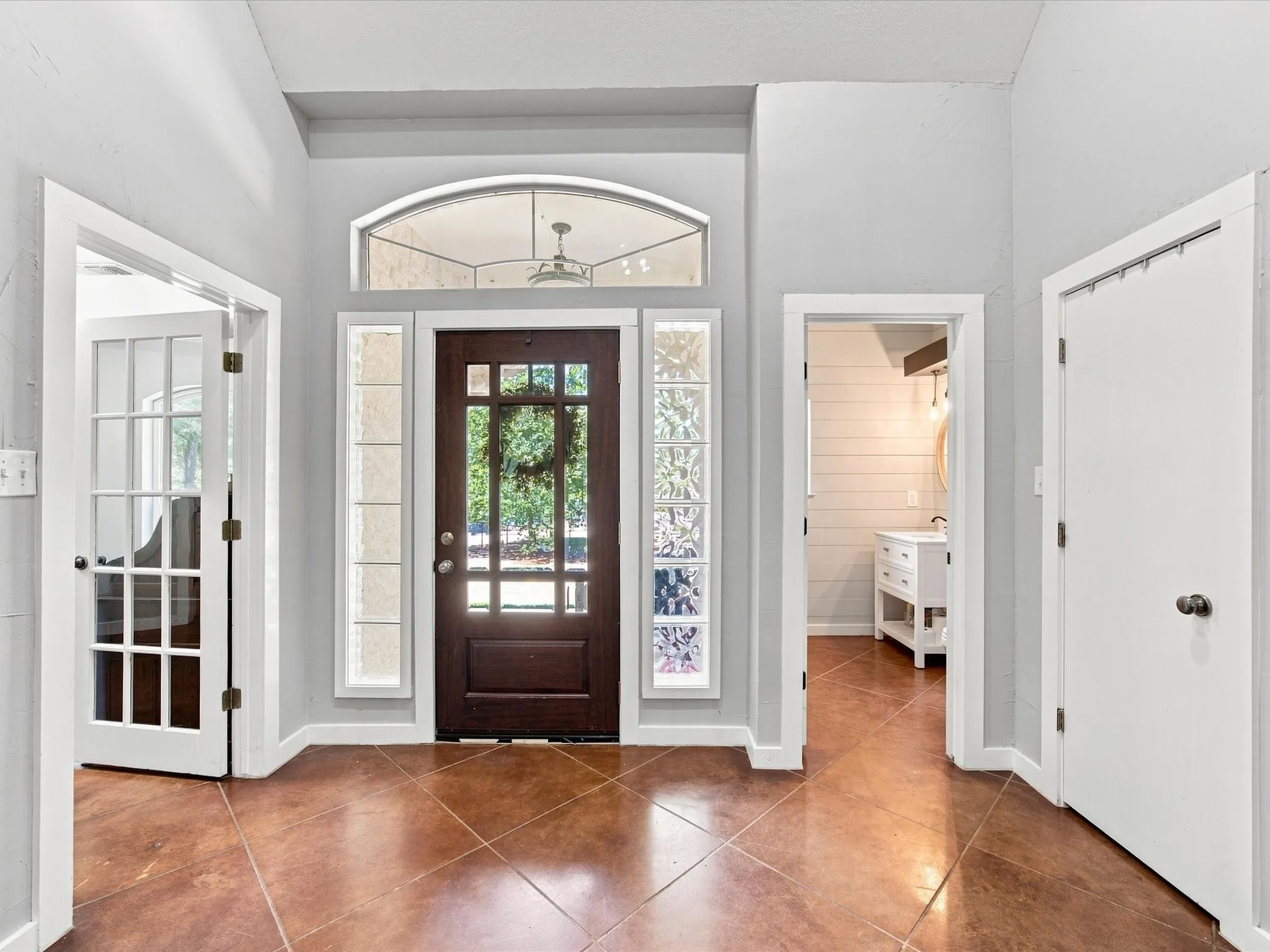 Arched transom window, side light windows, full-light front door, French doors, and diagonal floor tiling