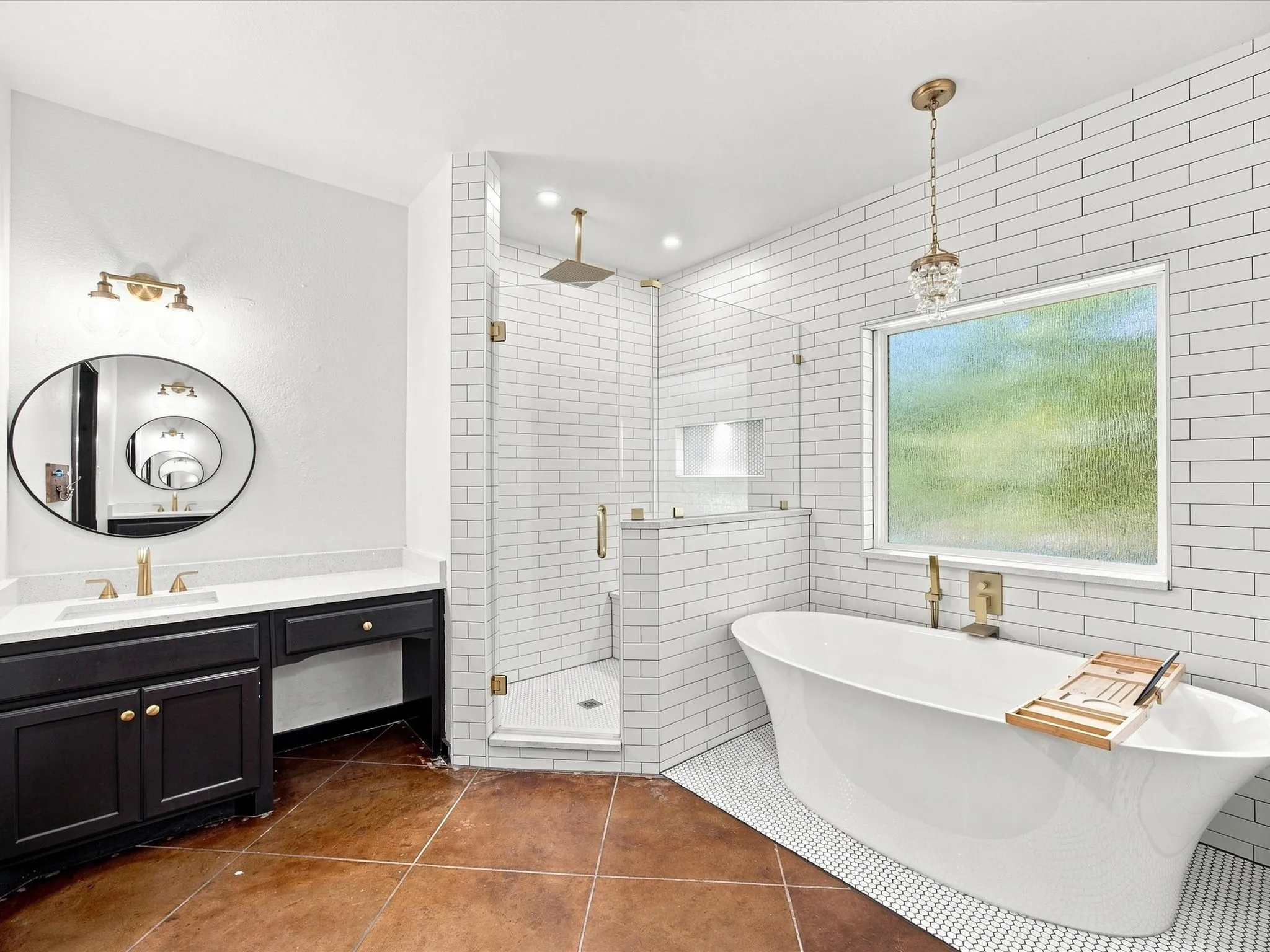 Freestanding soaking tub, glass-enclosed shower with subway tile surround, dual vanity with undermount sinks, and a circular mirror