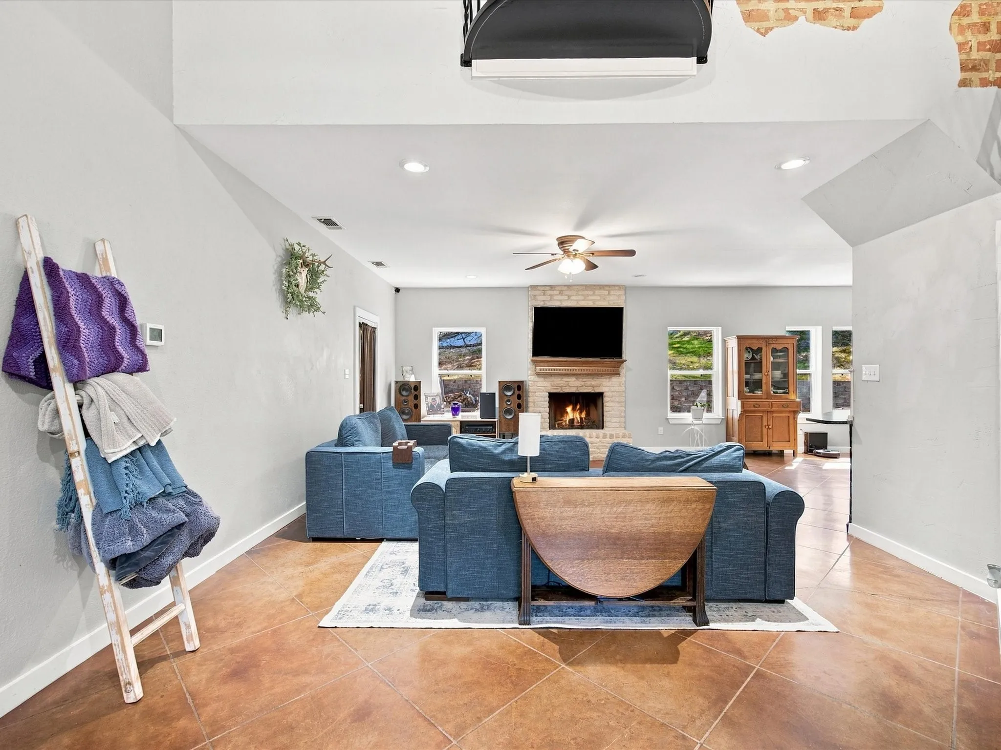 Spacious living area featuring polished concrete-look tile flooring, recessed lighting, and a ceiling fan