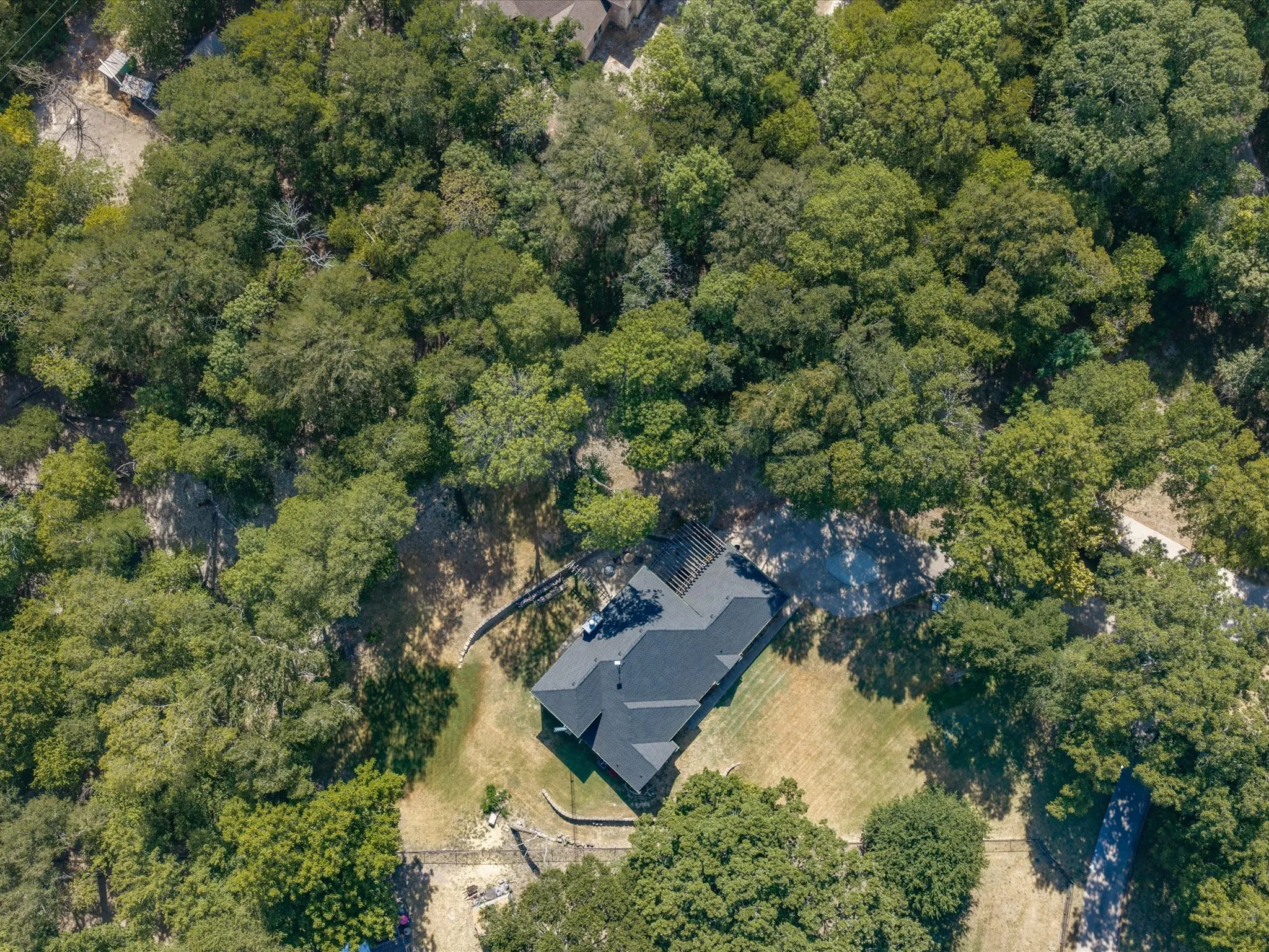 Expansive wooded property featuring a dark-toned roof and surrounding mature trees