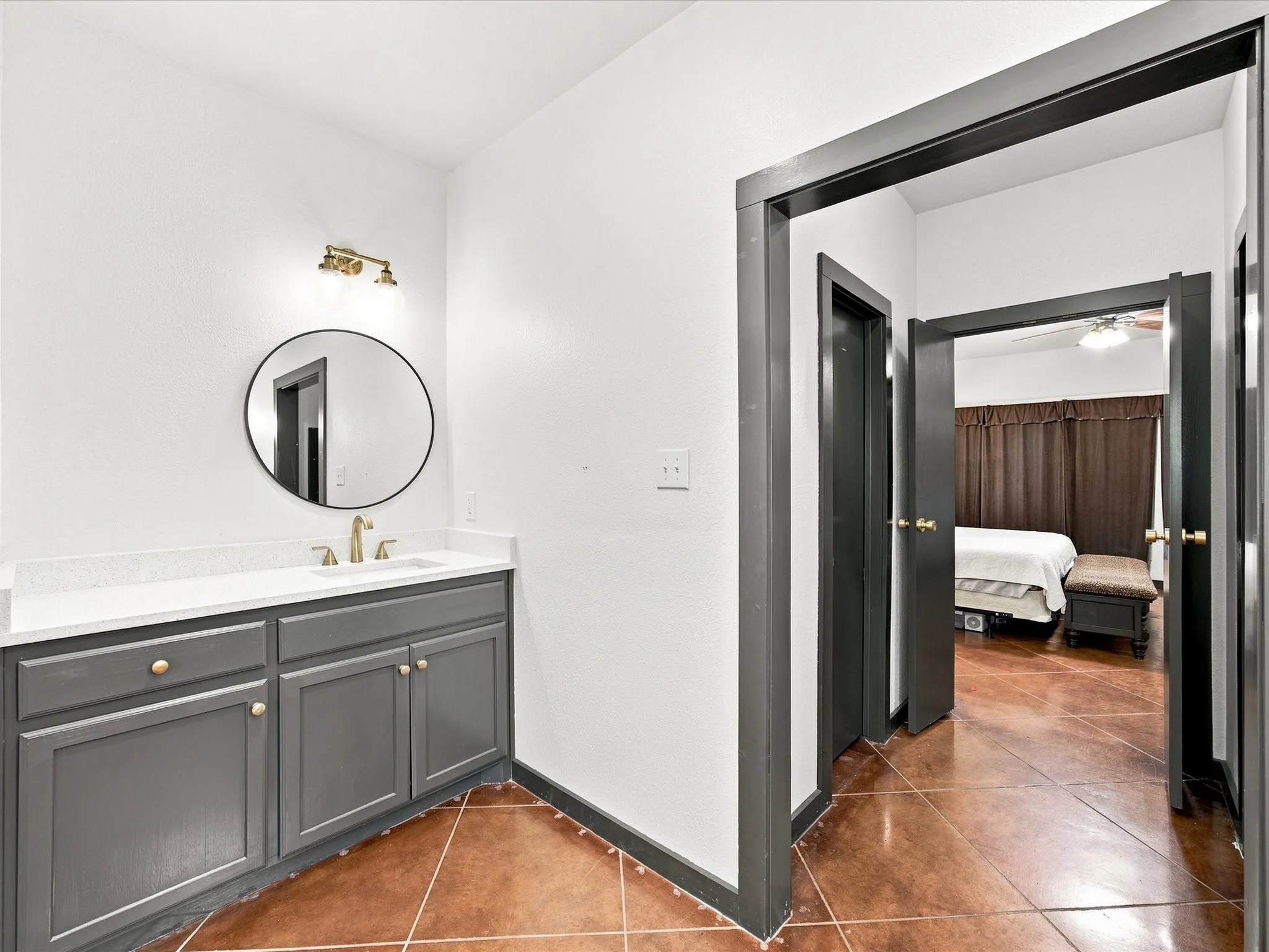 Vanity with gray cabinetry, white countertop, and gold-finish faucet