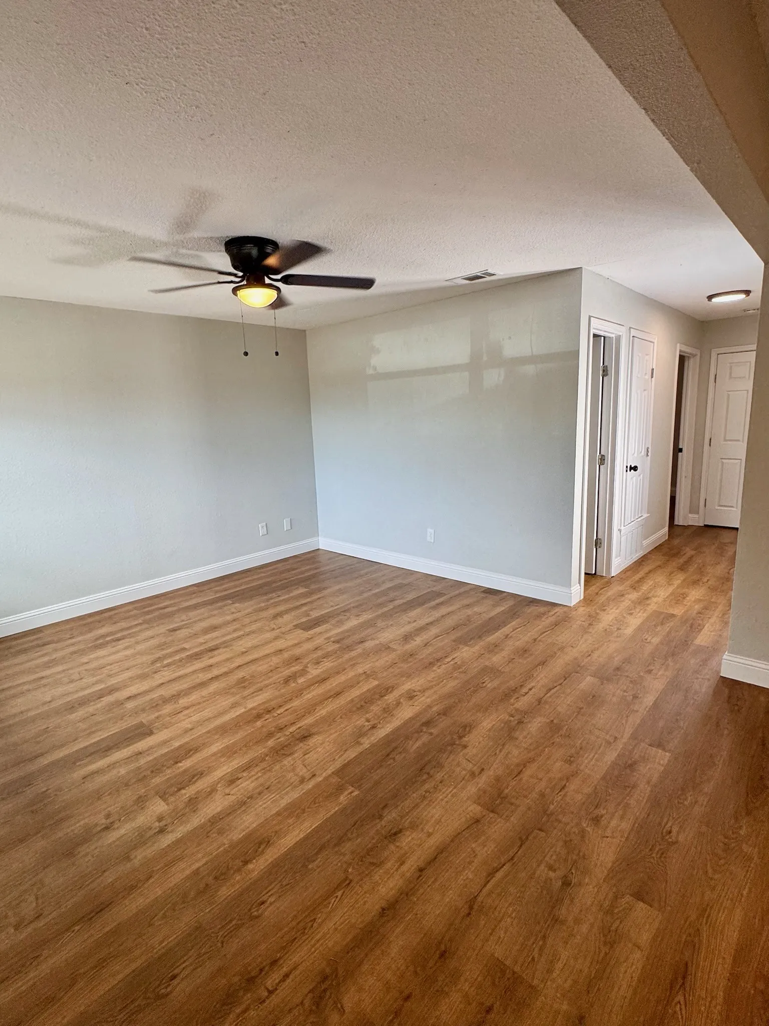 Wood-finish flooring throughout, ceiling fan with integrated lighting, recessed lighting, and white baseboards