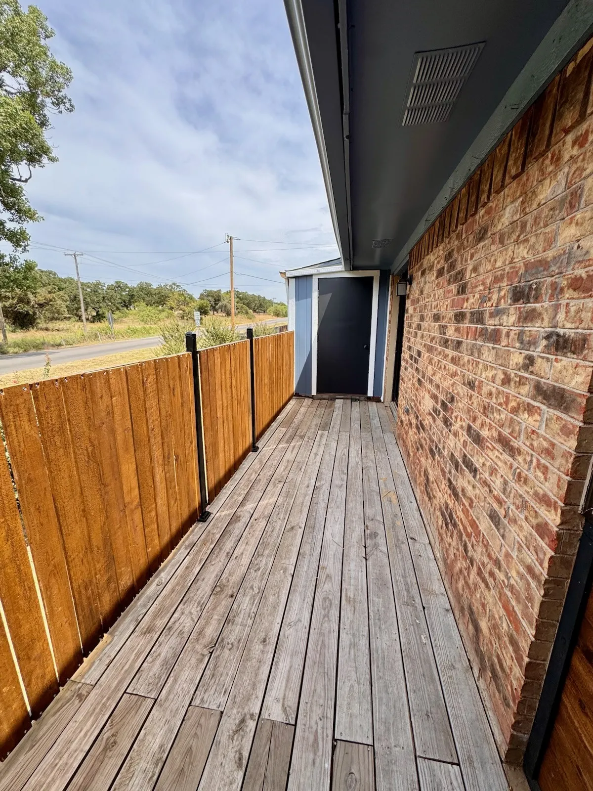 Brick exterior with a covered walkway and wood privacy fence