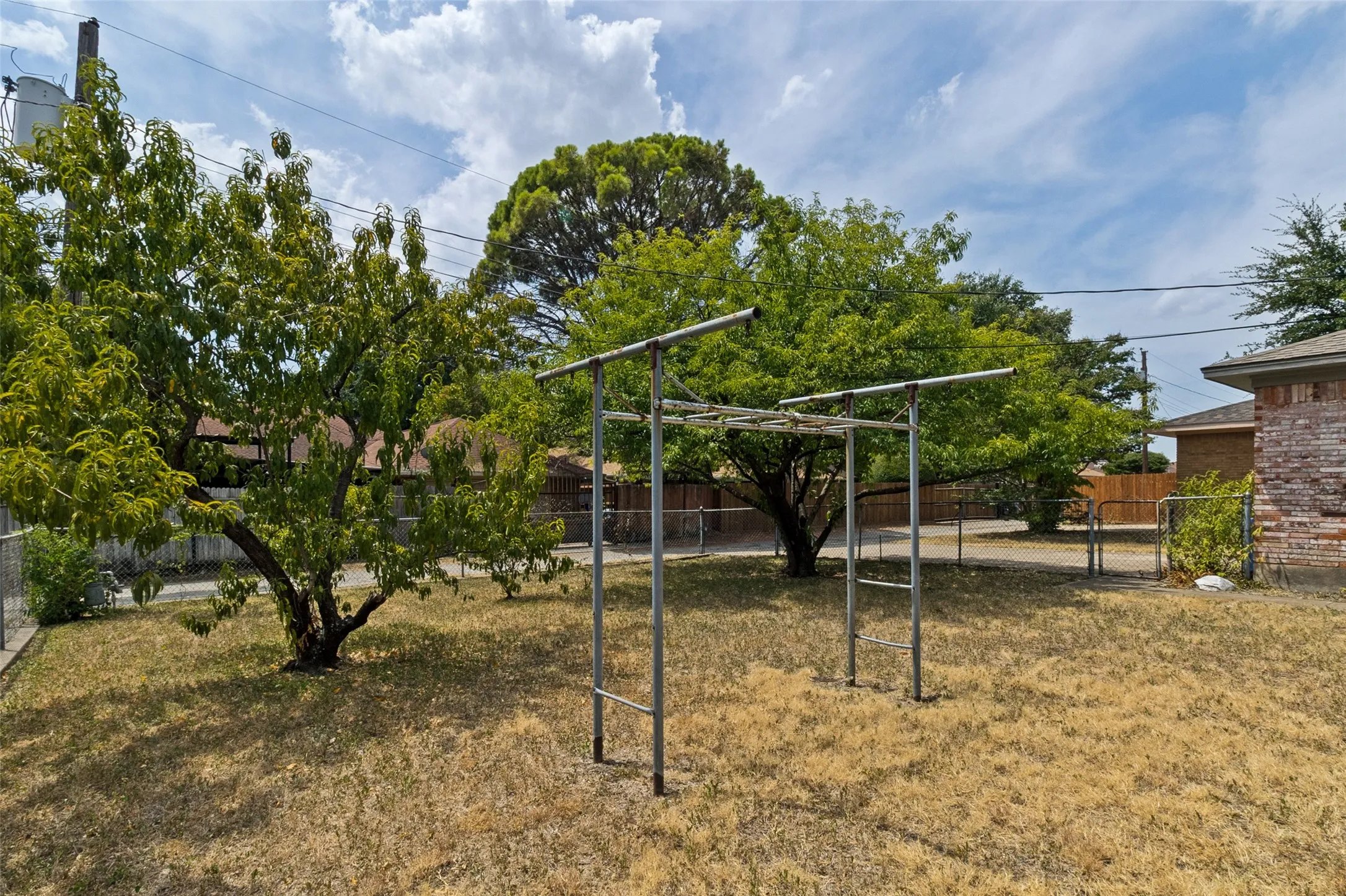 Spacious backyard area featuring mature trees and a chain-link fence
