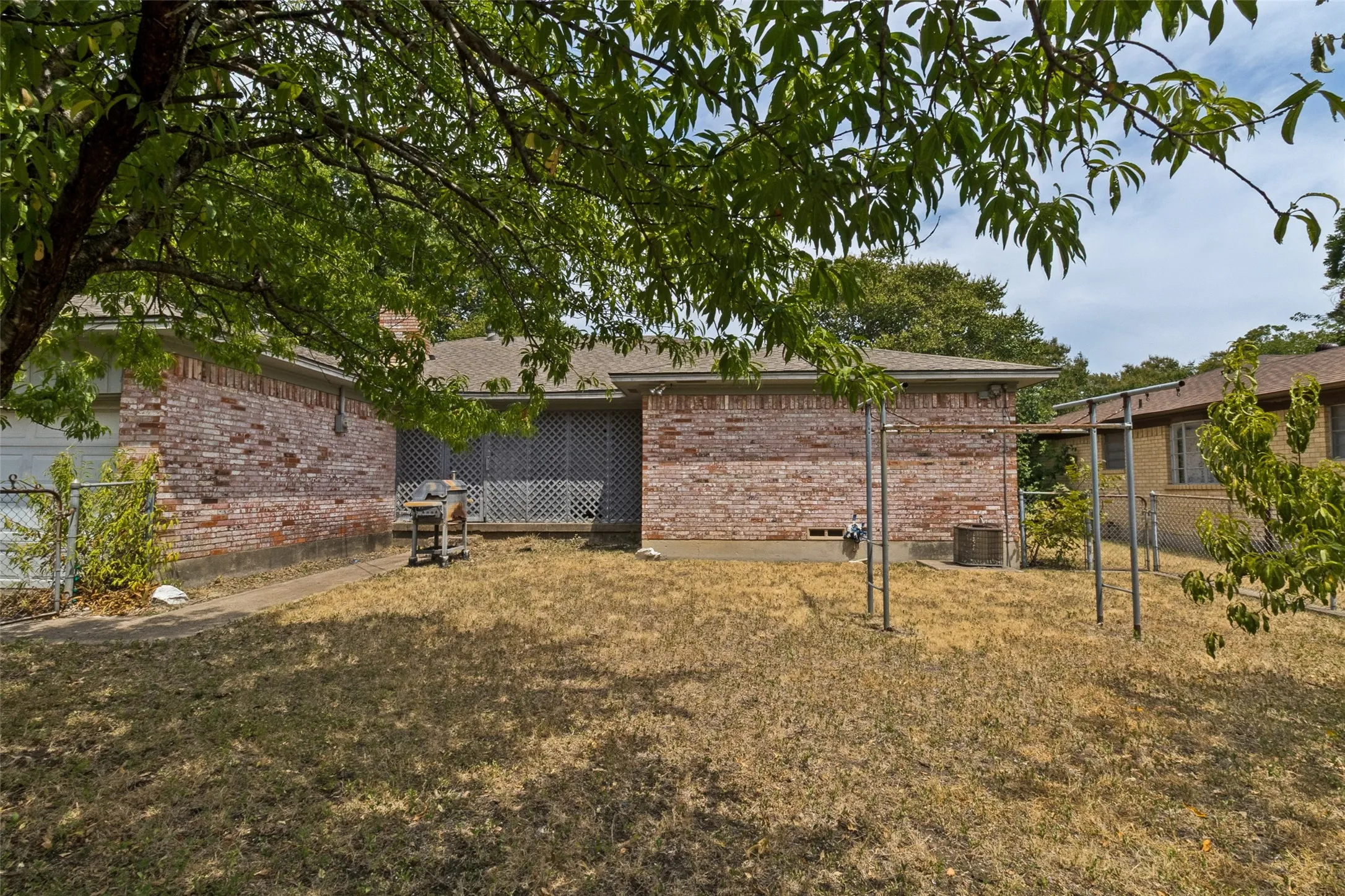 The view of the backyard shows an attached two car garage and a chain link fence.