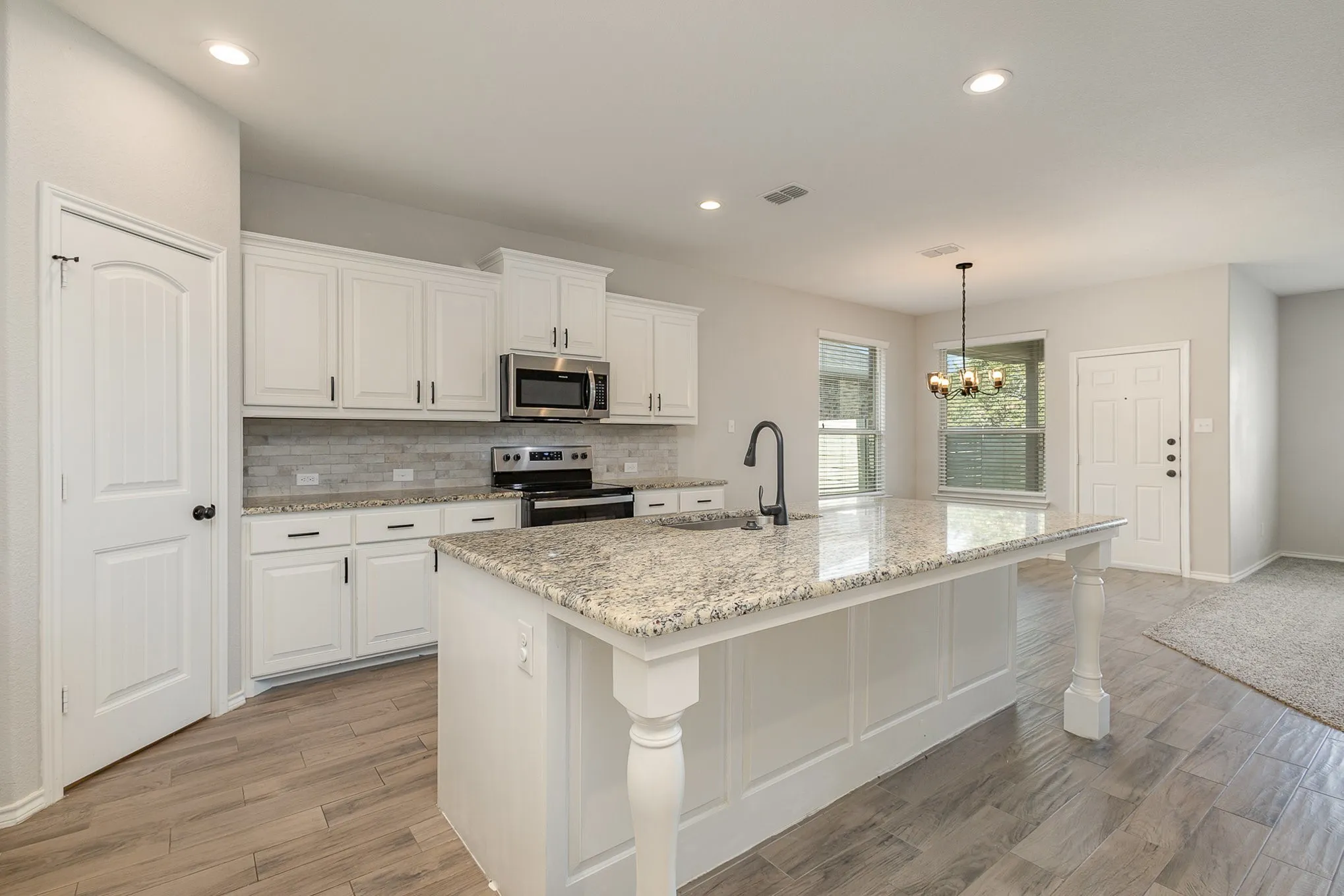 View of kitchen and dining area. Large kitchen island with designated sitting area, sink, granite countertops.