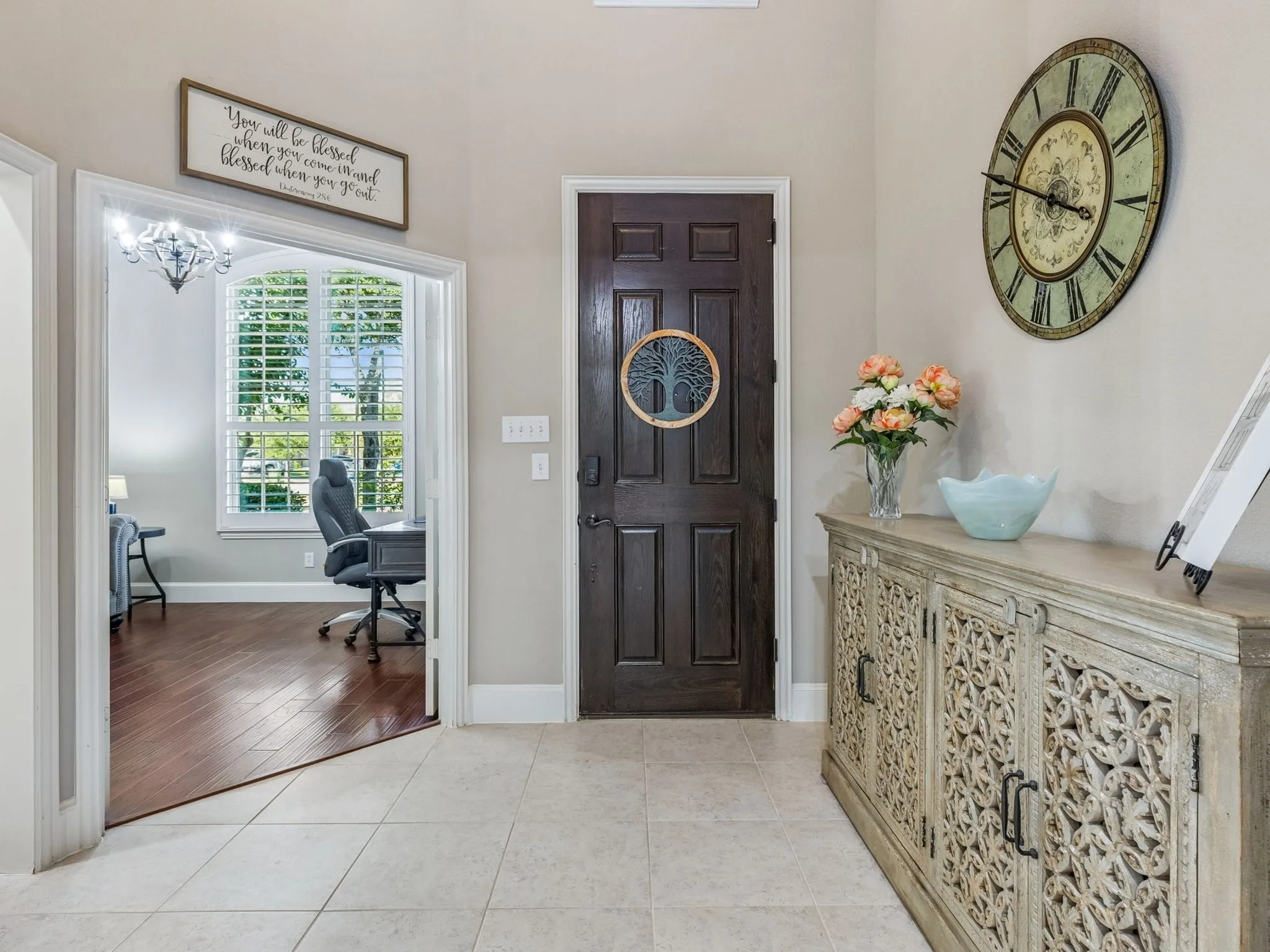Entryway featuring tile flooring, a dark wood-paneled door. and a office with french doors.