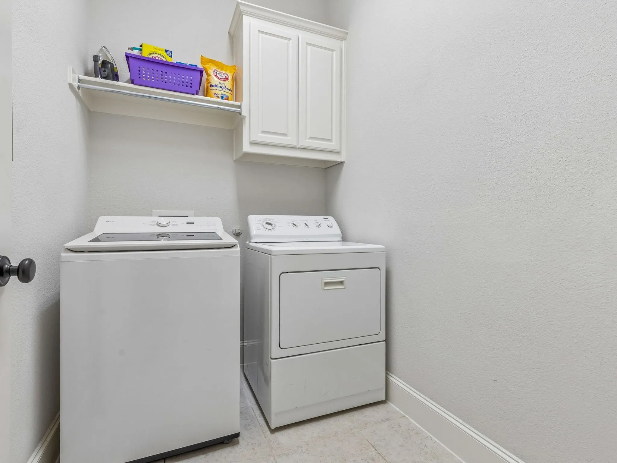 Built-in upper cabinetry, wall-mounted shelving, and light-toned tile flooring.