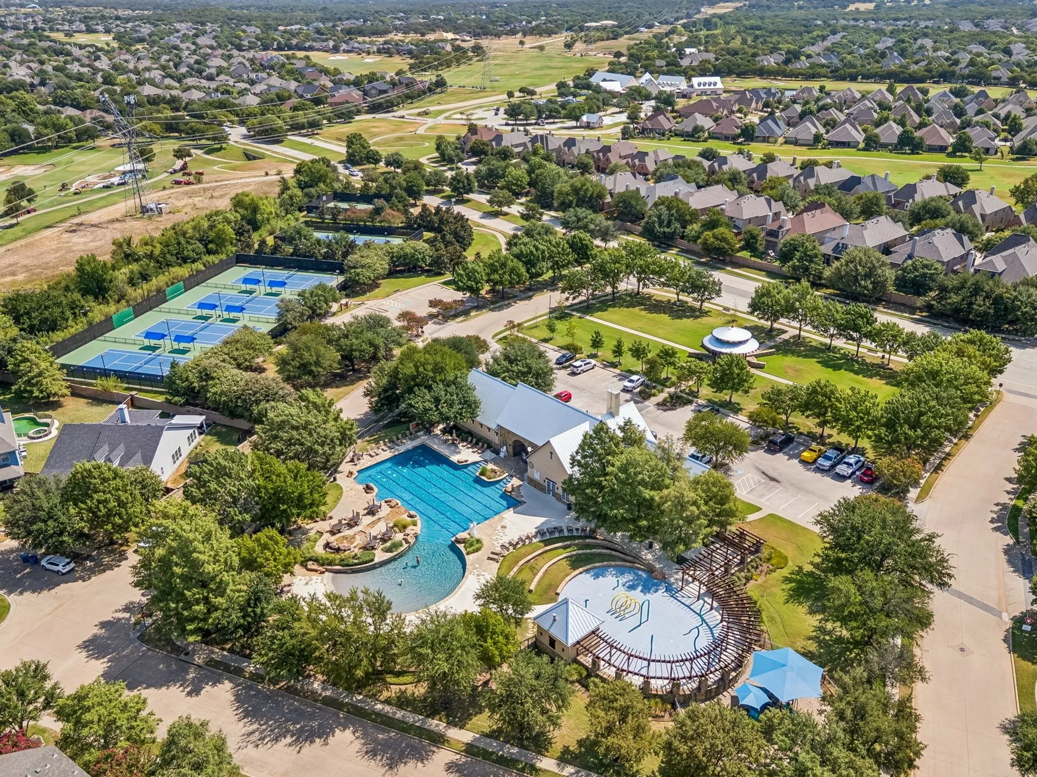 Community amenities featuring multiple tennis courts, a large swimming pool, a separate recreation pool, a park area, and a recreation building.