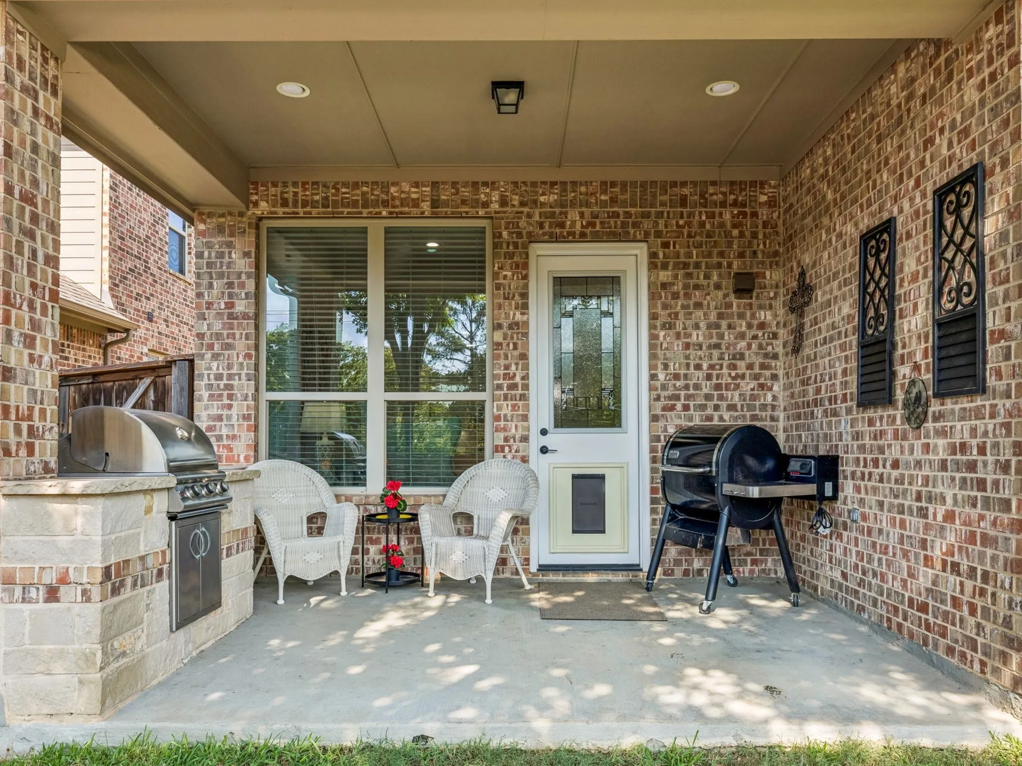 Covered patio with brick exterior, concrete flooring, and built-in grill station.