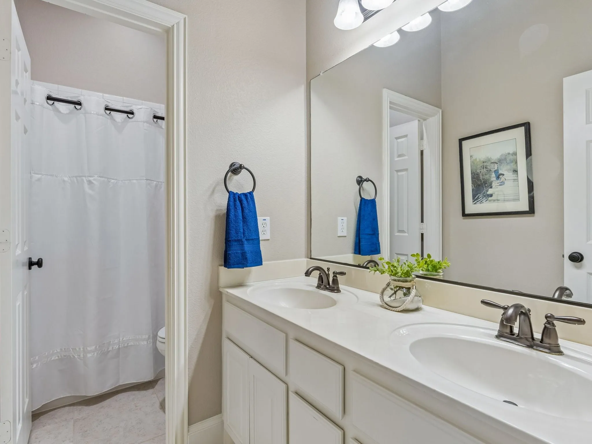Dual vanity with integrated sinks, brushed bronze fixtures, and an expansive wall-mounted mirror.