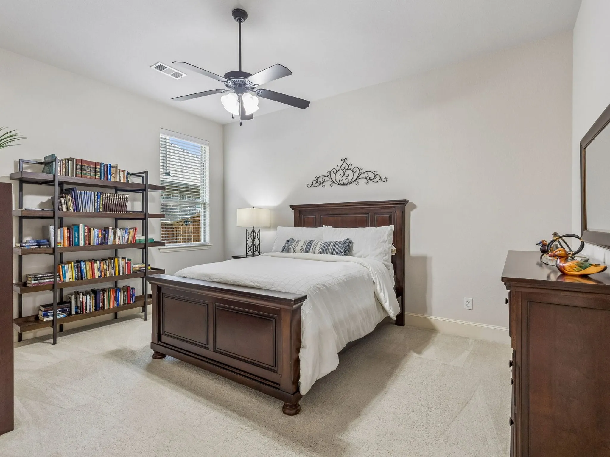 Ceiling fan with lighting, window with blinds, light-colored carpeting, and neutral wall tones.