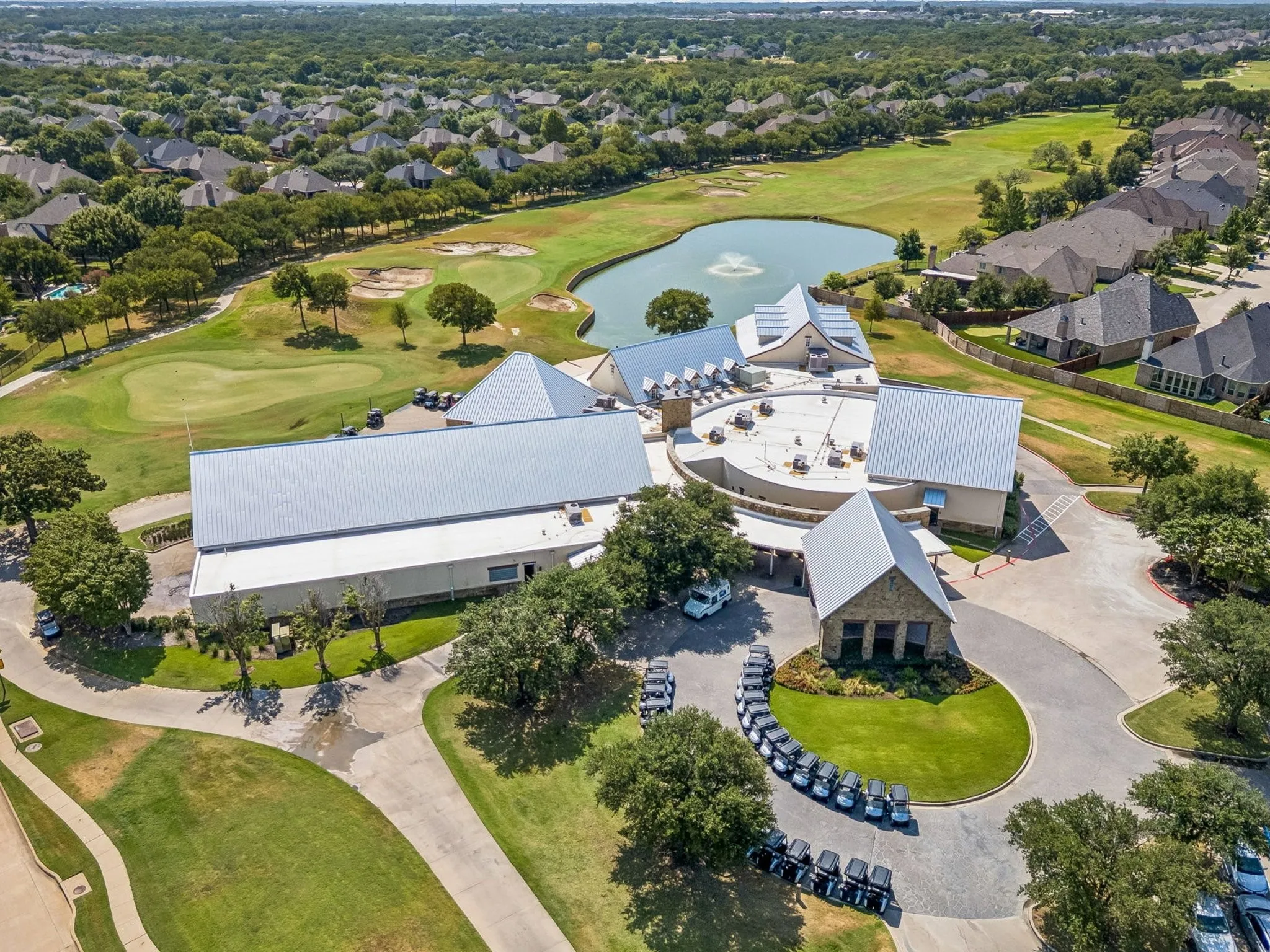 Expansive golf course with multiple greens, a water feature, and surrounding residences.