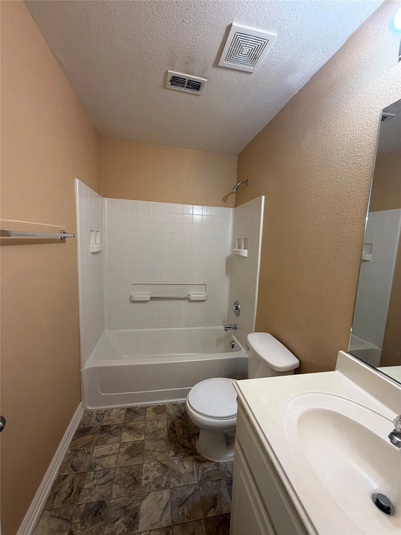 Built-in bathtub with white tile surround, vanity with an integrated sink, and patterned floor tiles