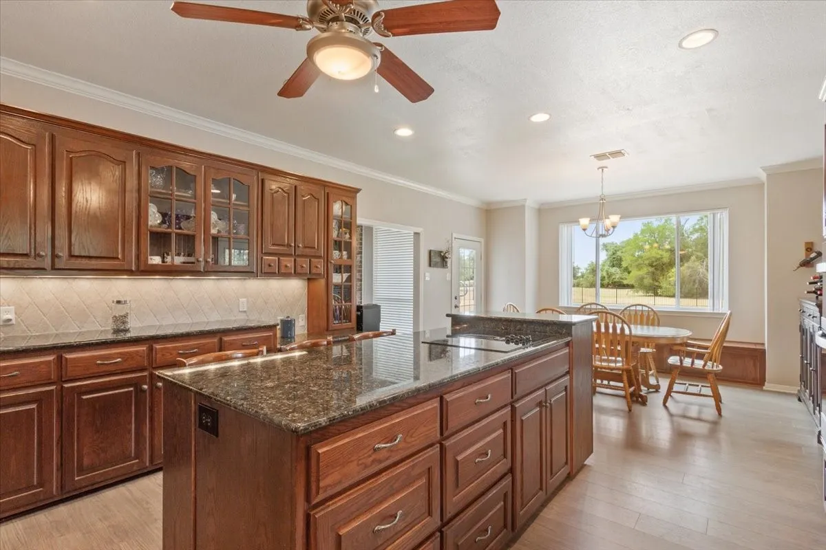 Spacious kitchen featuring wood-finish cabinetry, dark stone countertops, a large kitchen island, and recessed lighting