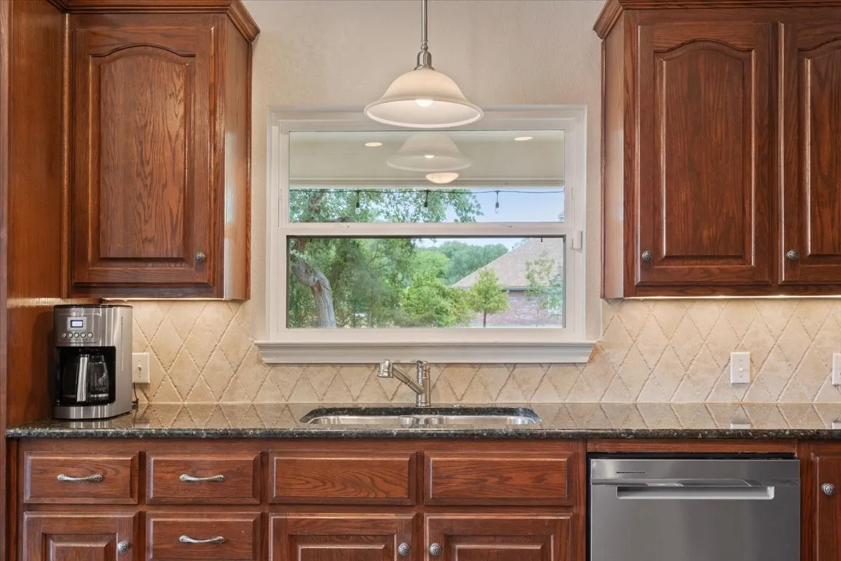 Warm wood cabinetry with arched details, granite-style countertops, and a diamond-patterned tile backsplash