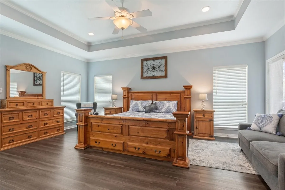 Tray ceiling with recessed lighting and a ceiling fan, wood-finish flooring, and multiple windows with blinds